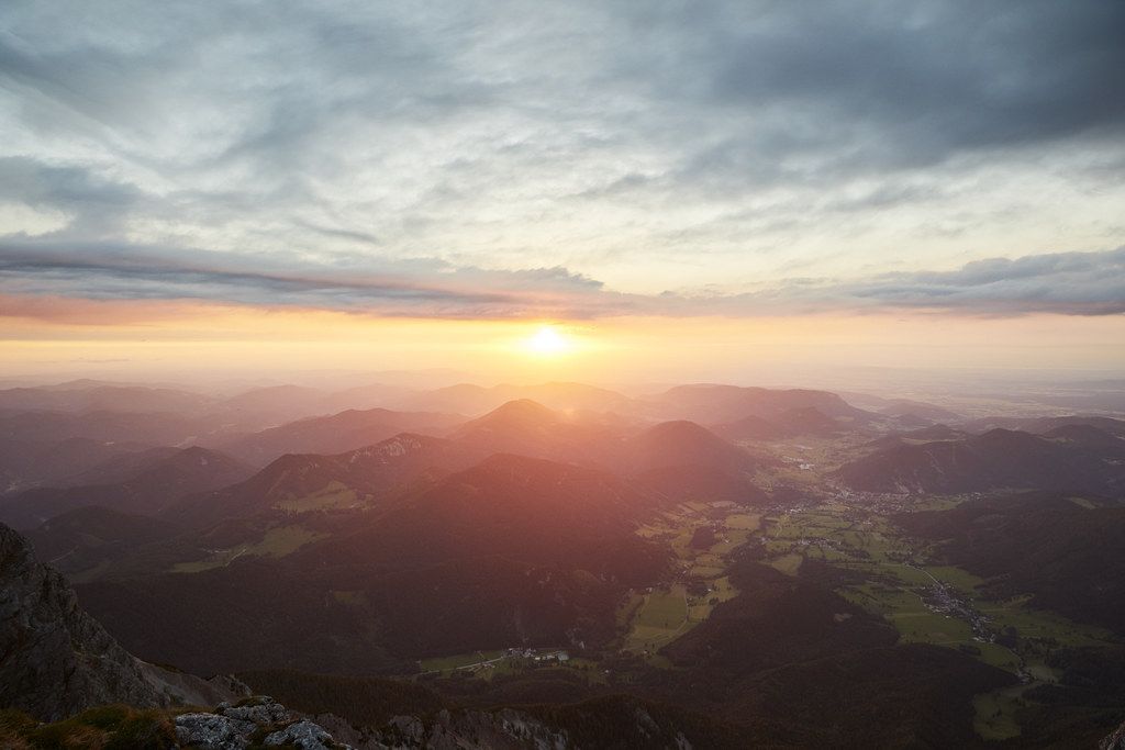 Sunset over a mountain landscape with clouds and valleys.