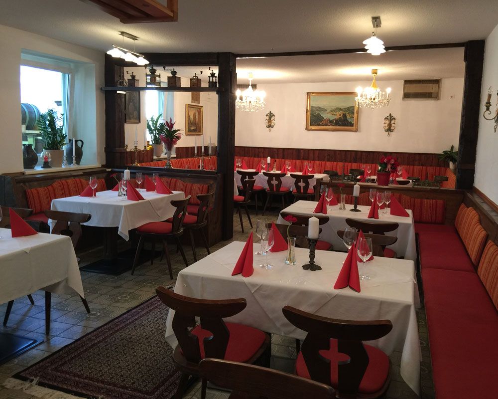 Interior view of a traditional pub with laid tables and red chairs.