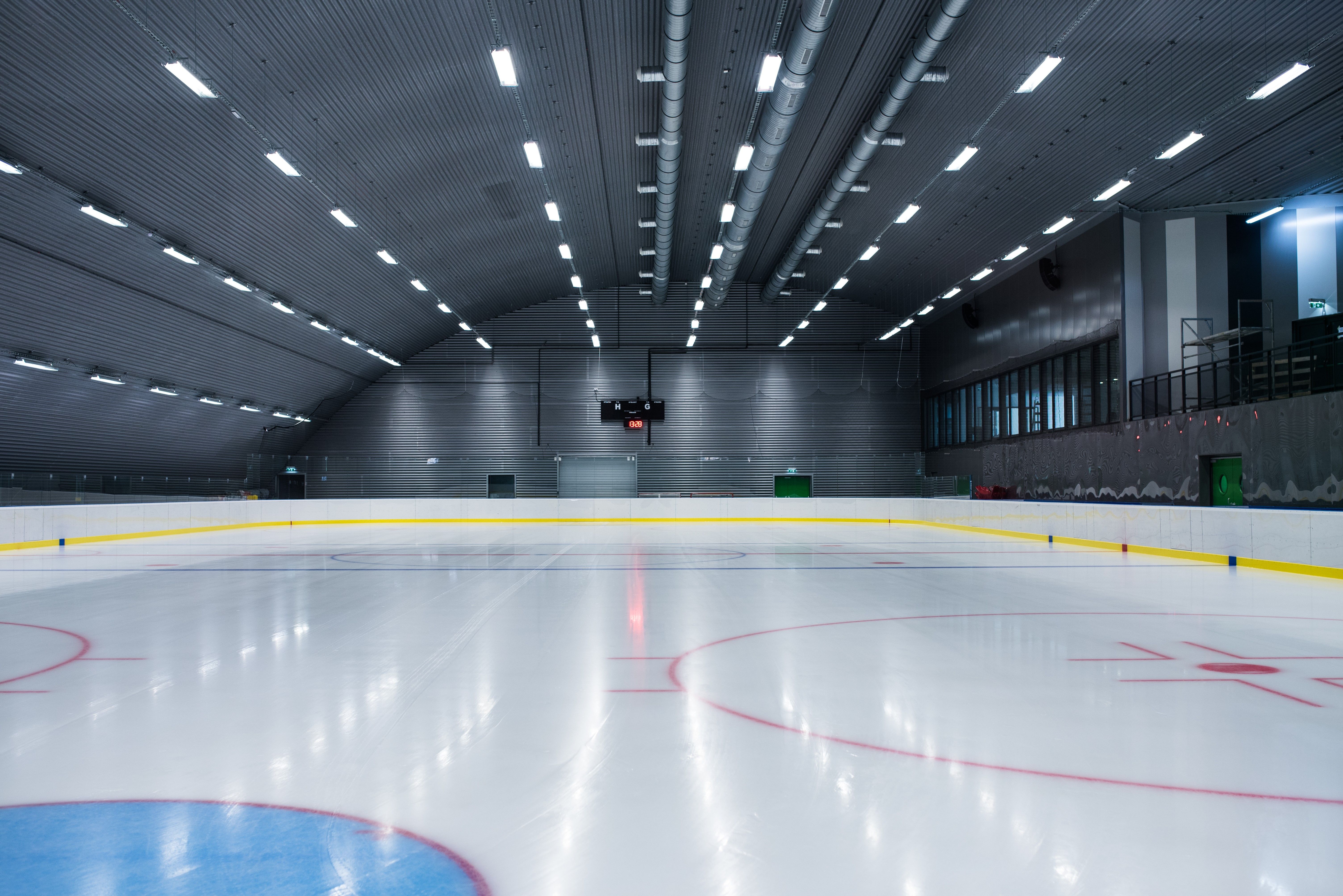 Empty ice rink with illuminated pitch and scoreboard.