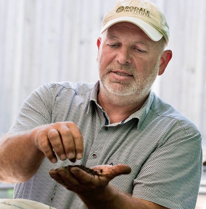 A man holds soil in his hand and lets it trickle through his fingers.