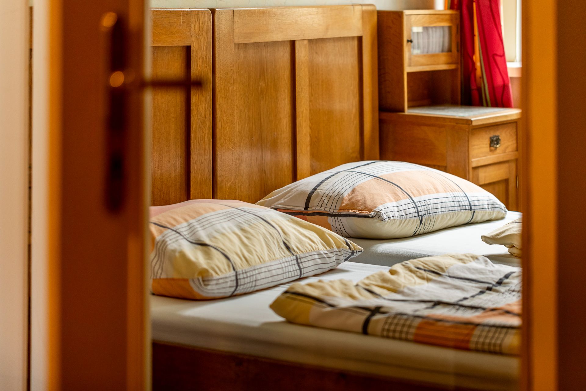 A cozy bedroom with wooden furniture and checkered pillows on the bed.