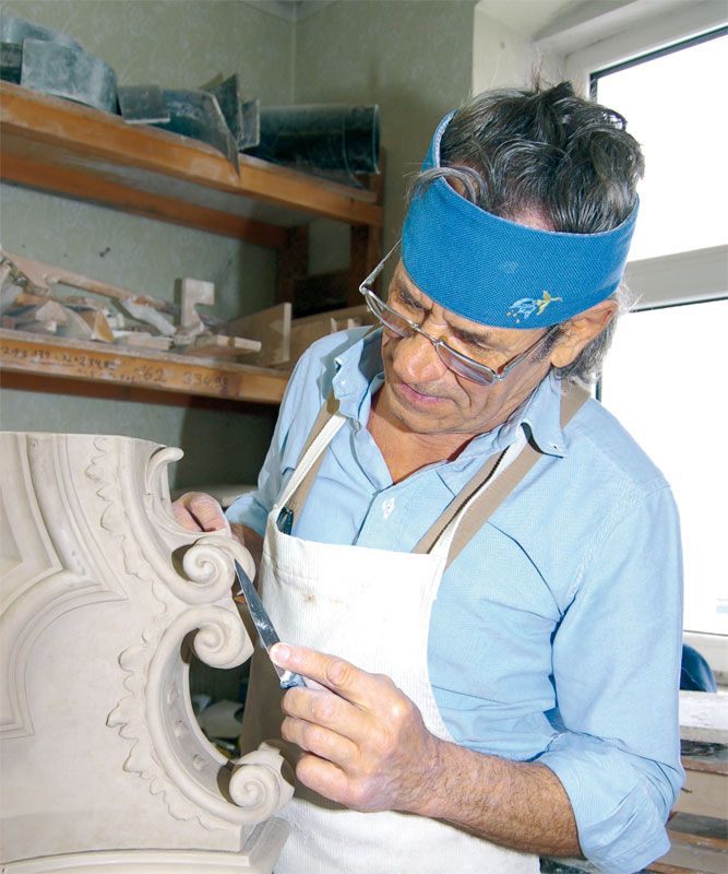 A restorer works on a decorative element with a tool.