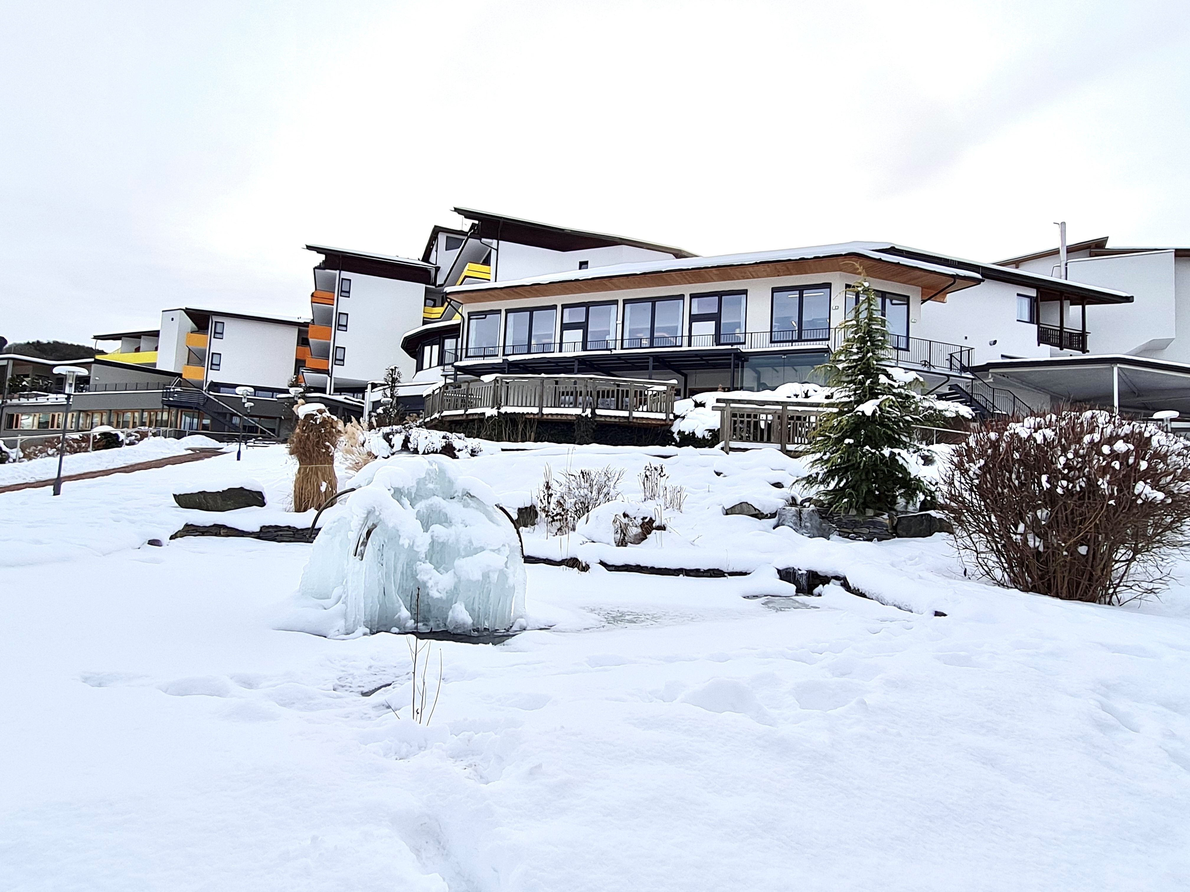 Snow-covered hotel building with frozen fountain in the foreground.