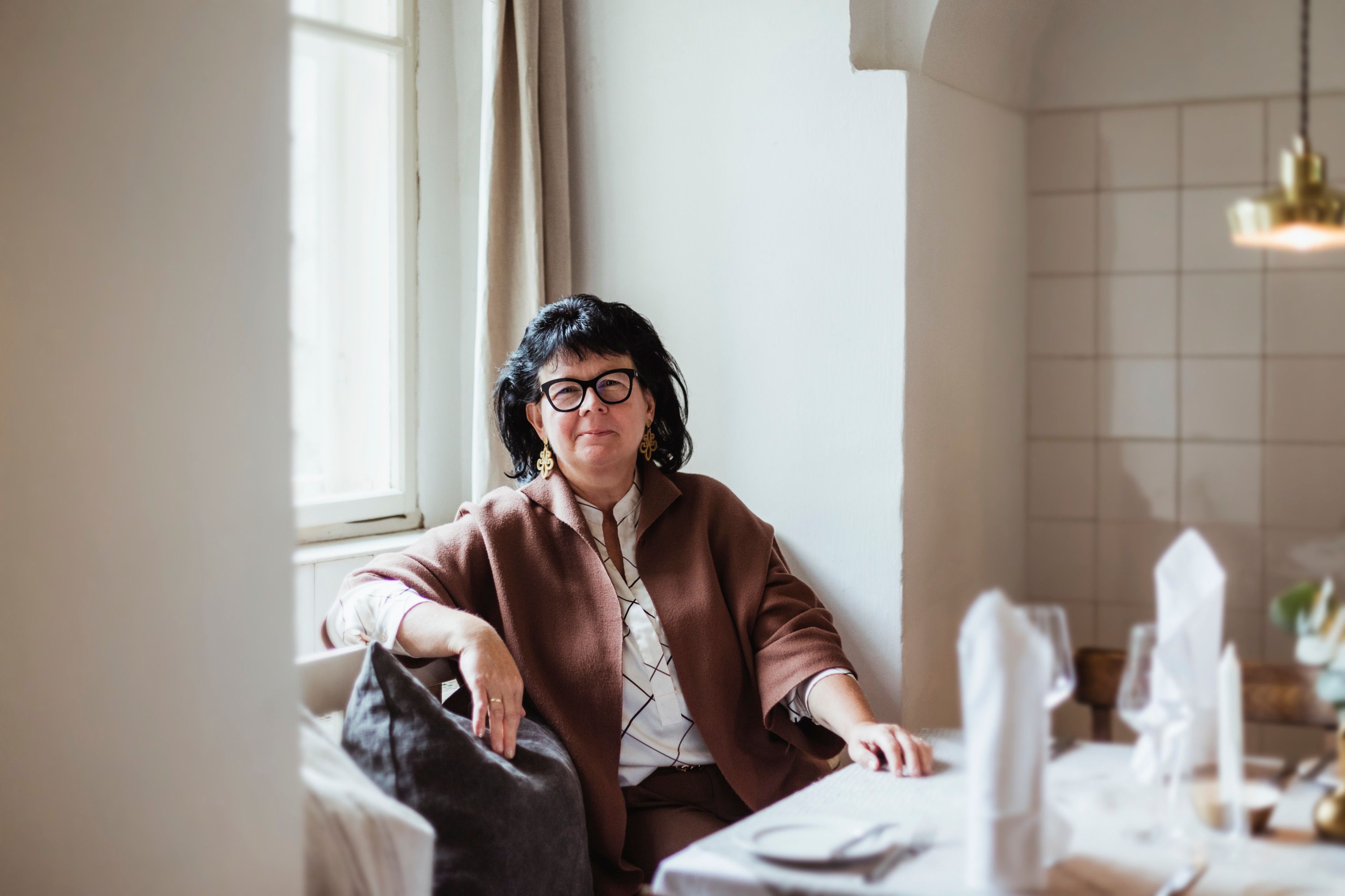 Woman sitting at a laid table in a cozy room.