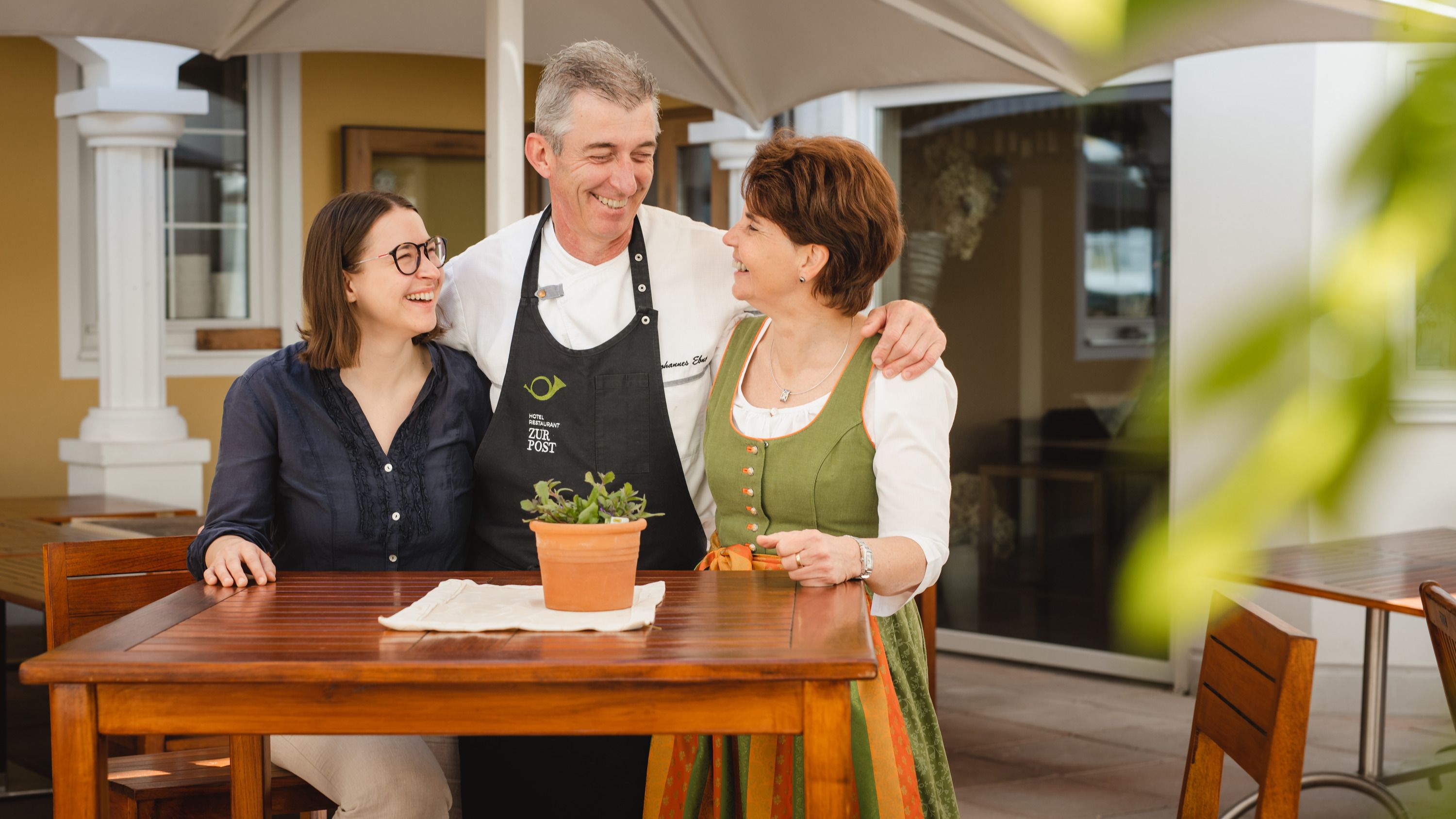 The Ebner family, the owners of the Hotel Zur Post, stand around an outdoor table.