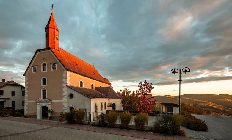Church in St. Corona am Wechsel at sunset with a cloudy sky.