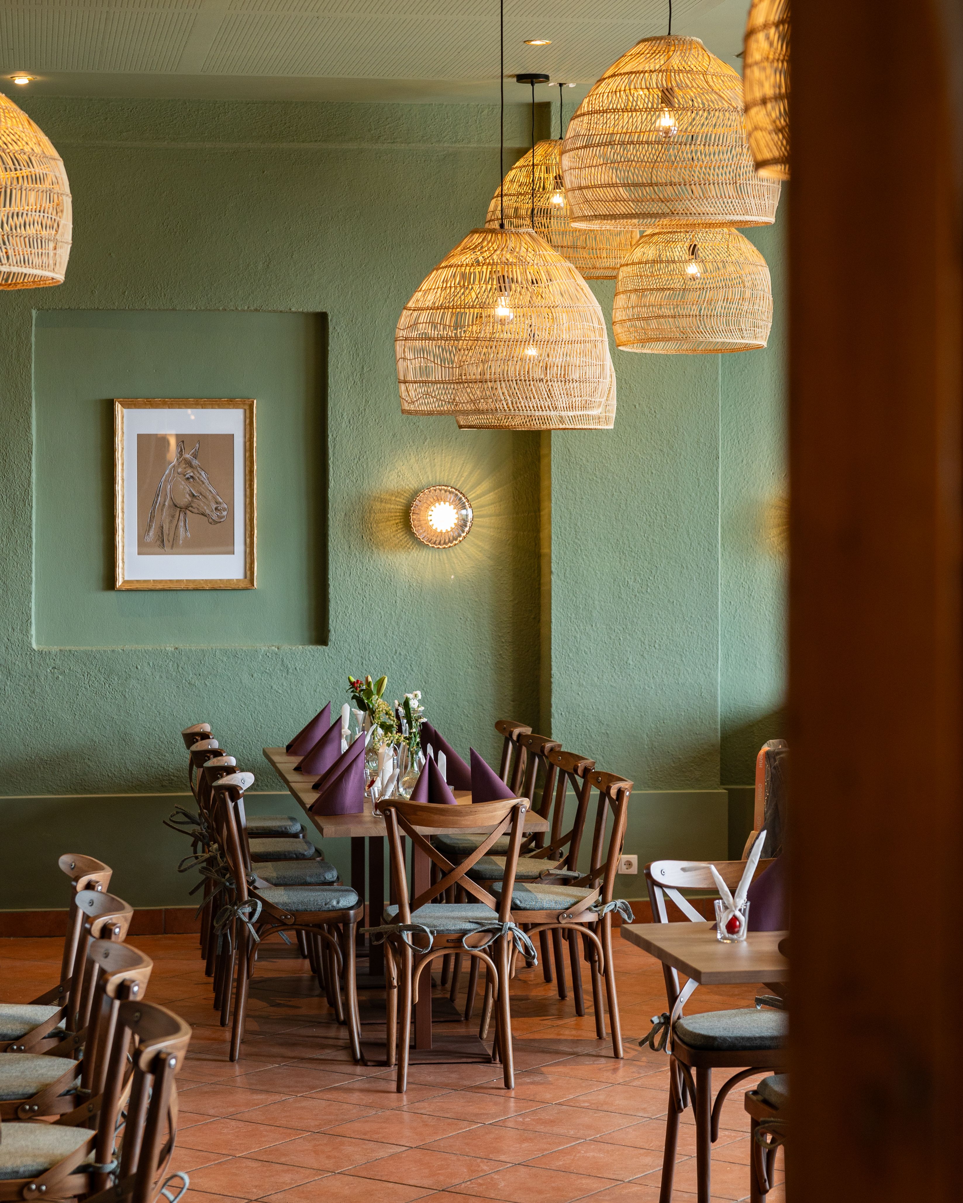 Cozy dining area with wooden table, chairs and woven lamps.
