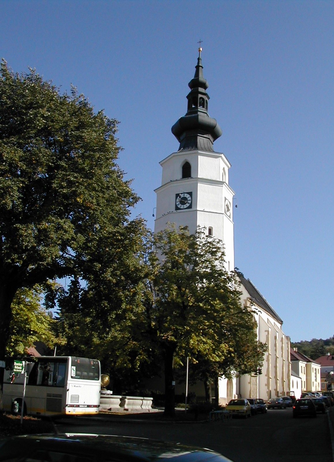 Königstetten parish church with tower and trees in the foreground.