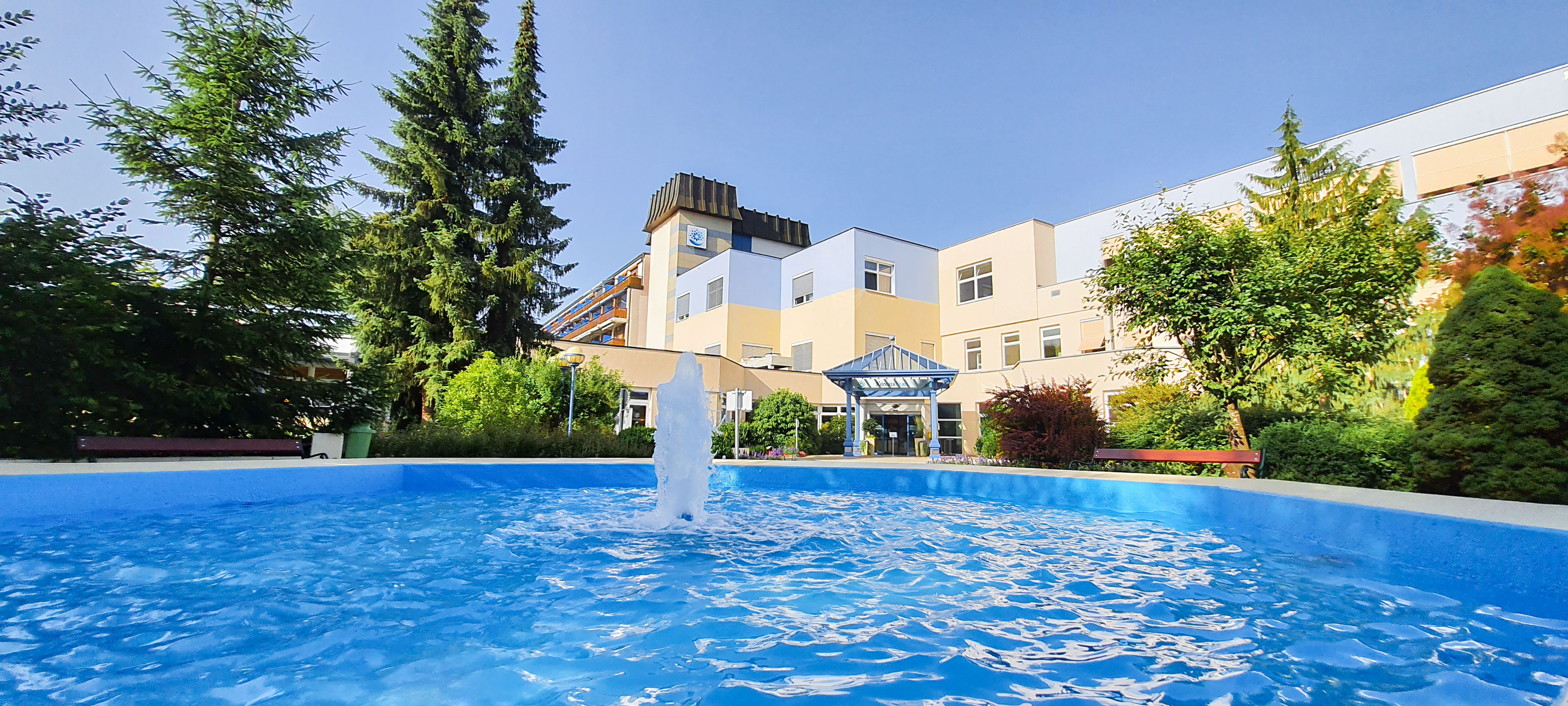 Exterior view of a health resort with fountain and garden.