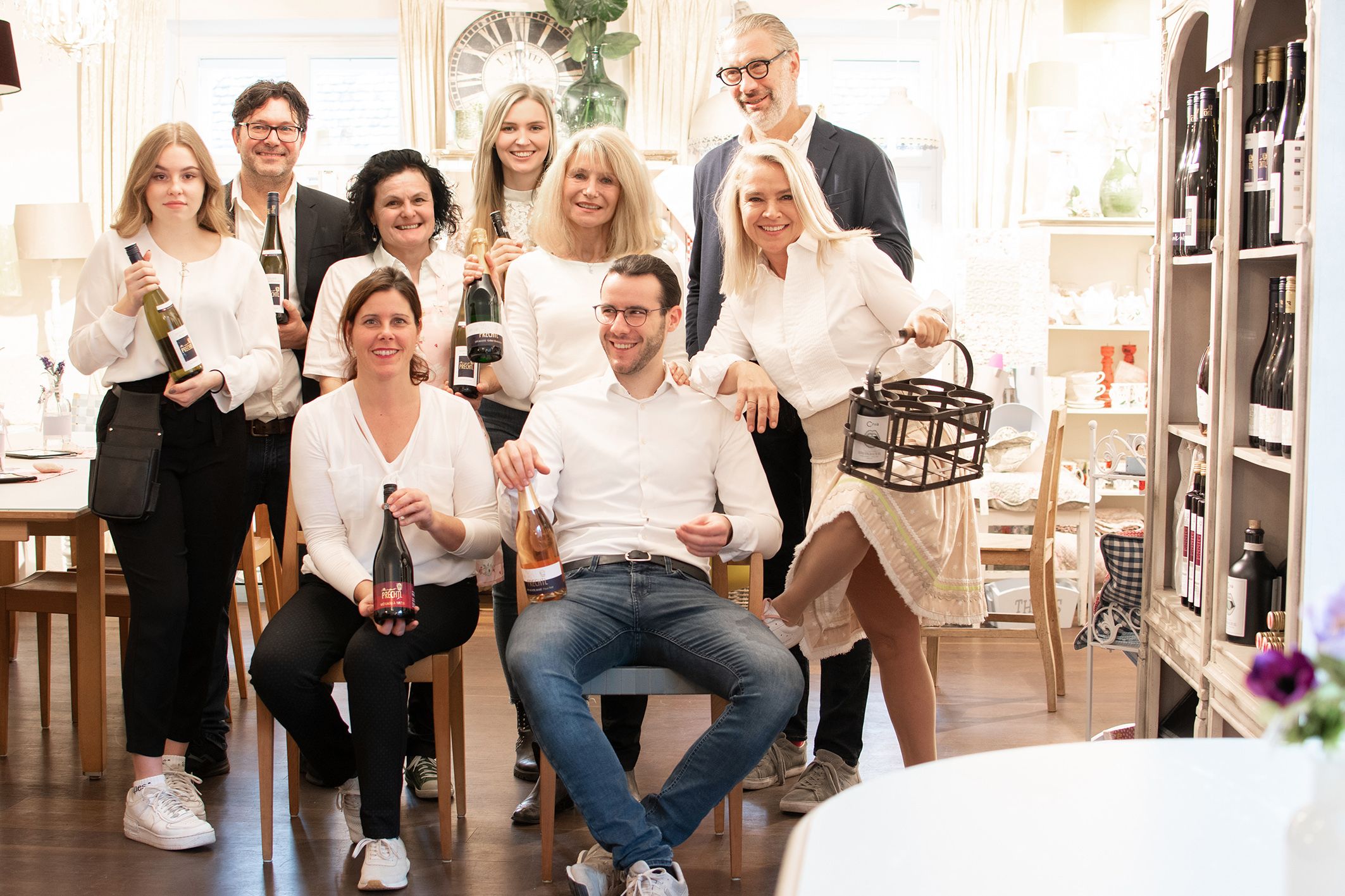 Group of people in a room with bottles of wine.