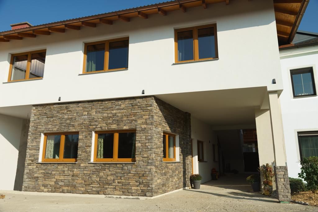 Modern house façade with white plaster and natural stone cladding.