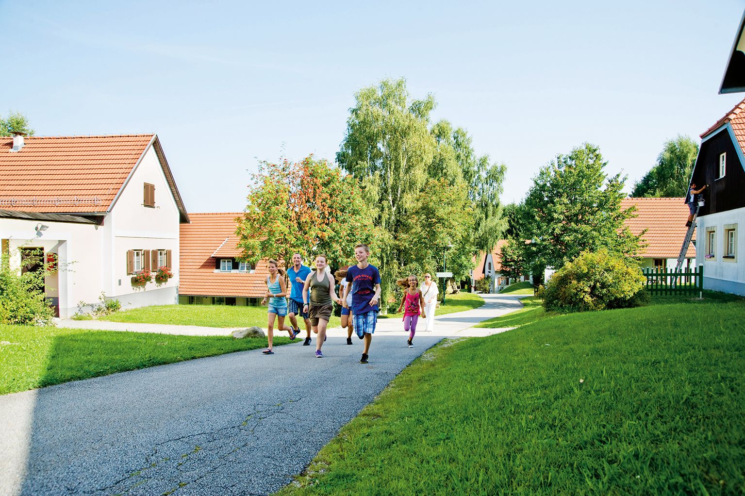 Group of people walking on a path in a vacation village with red roofs and green surroundings.