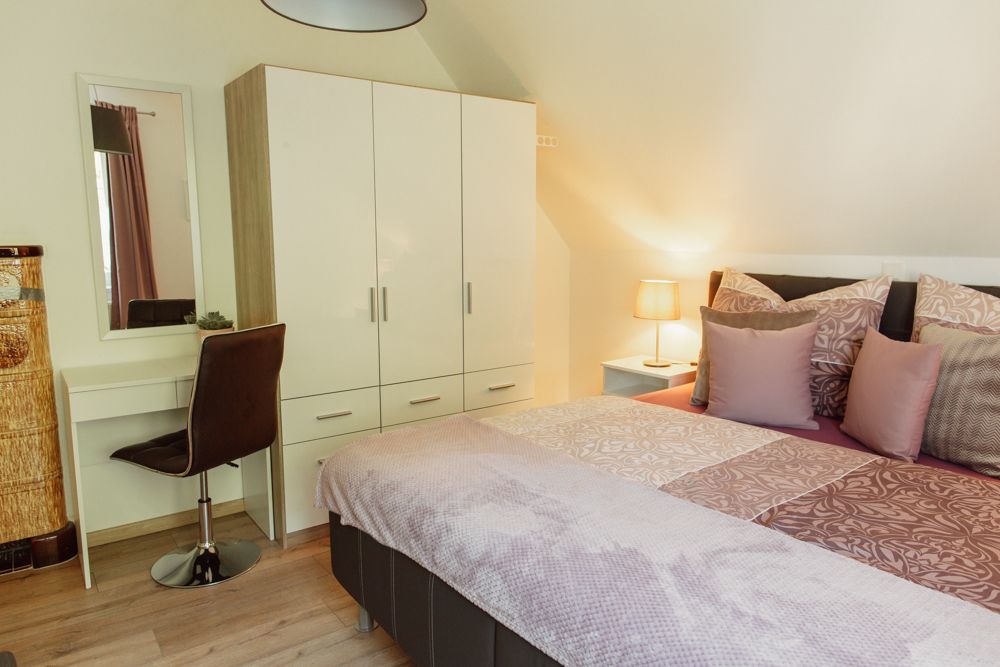 Bedroom with double bed, closet, dressing table and lamp.