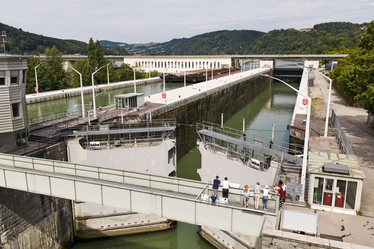A group of visitors watches a ship enter the lock chamber while the tour guide explains how the lock works.