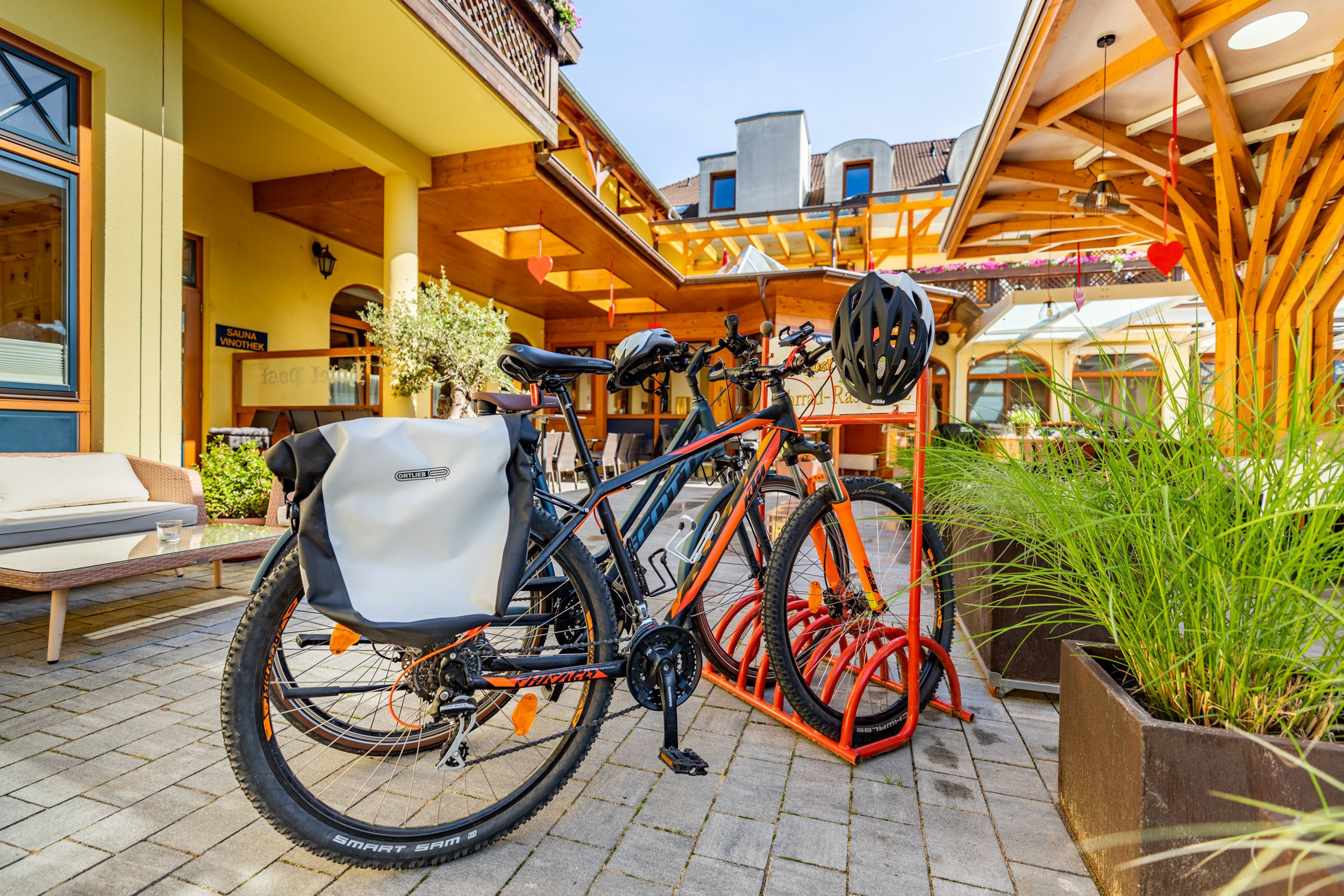 Bicycles on a bicycle stand in front of a hotel building.
