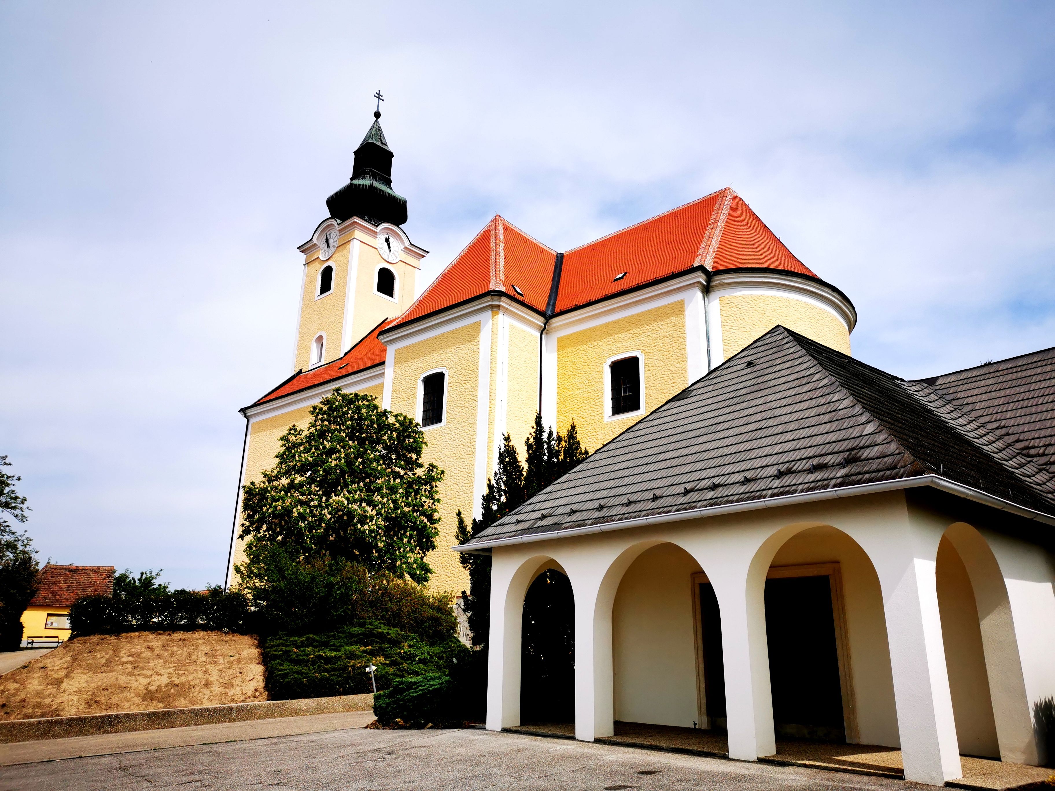 St. Nicholas parish church in Röschitz with yellow façade and red roof.