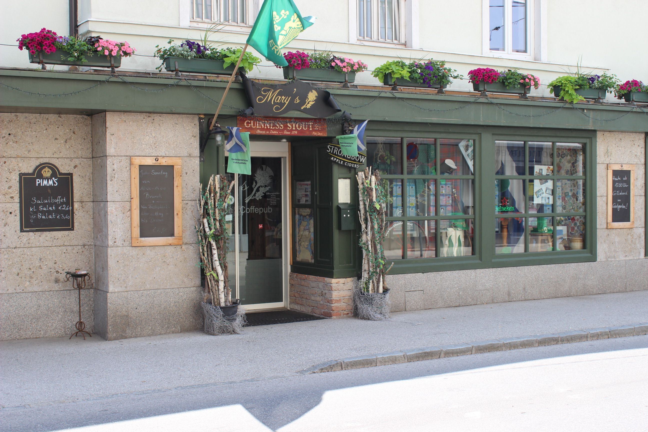Entrance to a pub with a green façade and flower boxes.