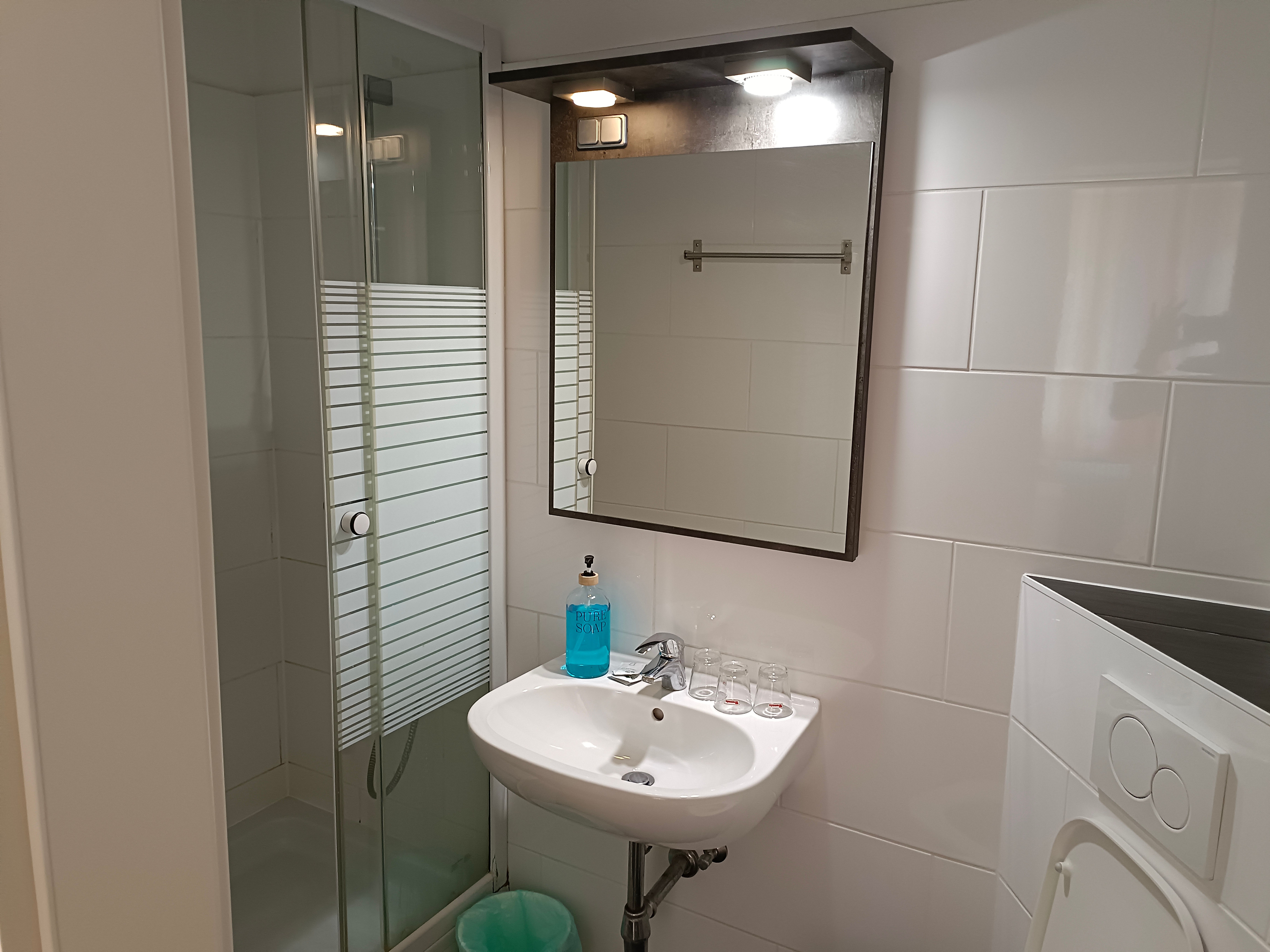 Modern bathroom with shower, washbasin and mirror.