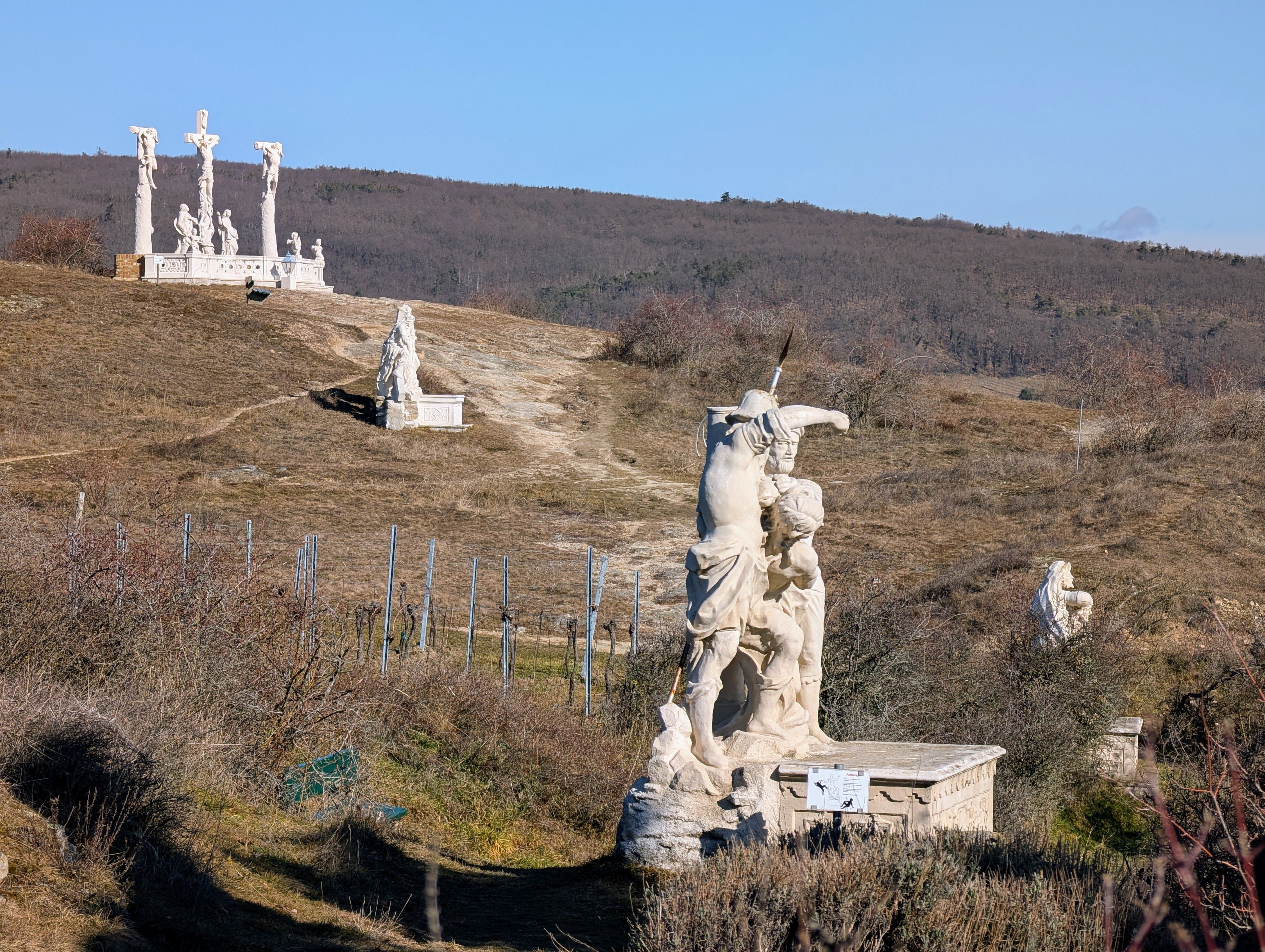 Calvary with several religious sculptures on a hill under a blue sky.