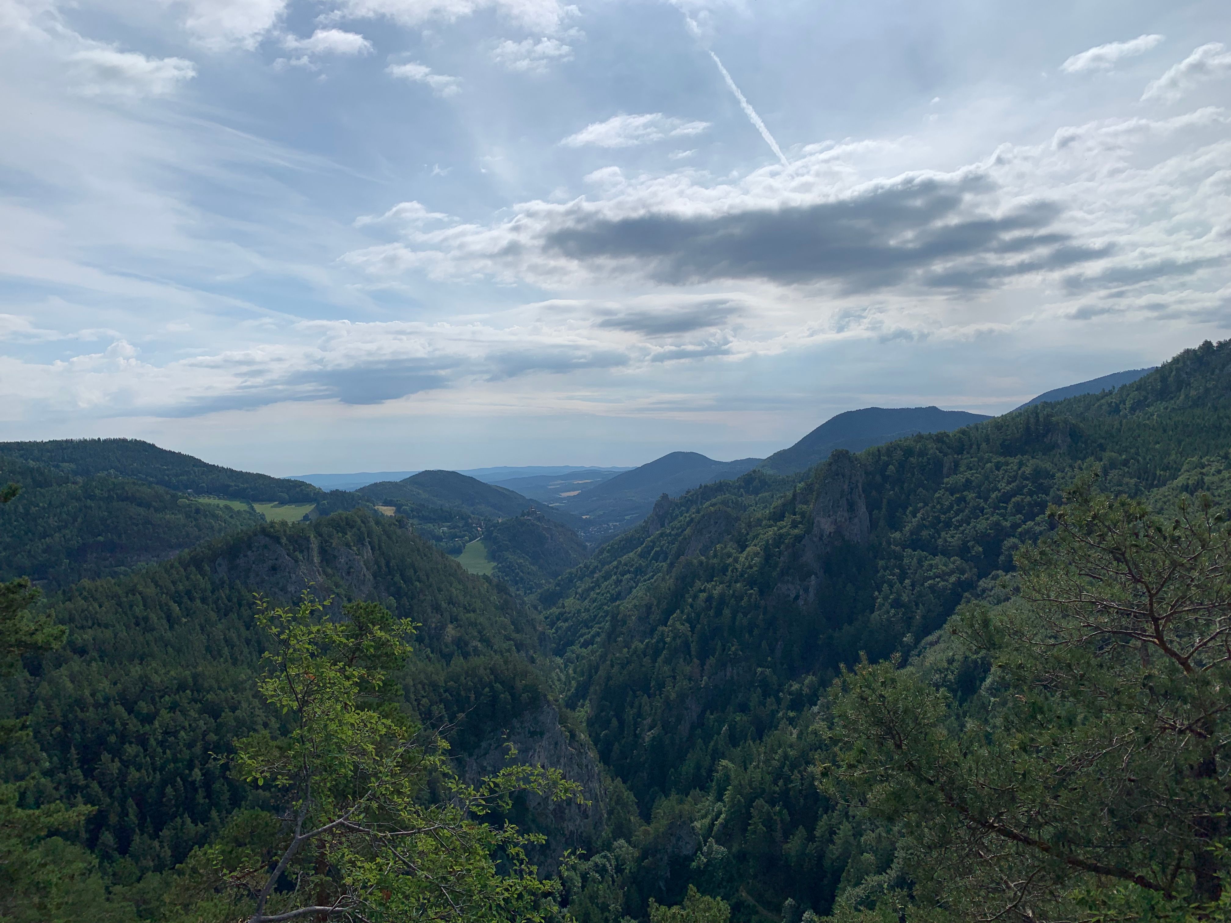View of wooded mountains and valleys under a cloudy sky.
