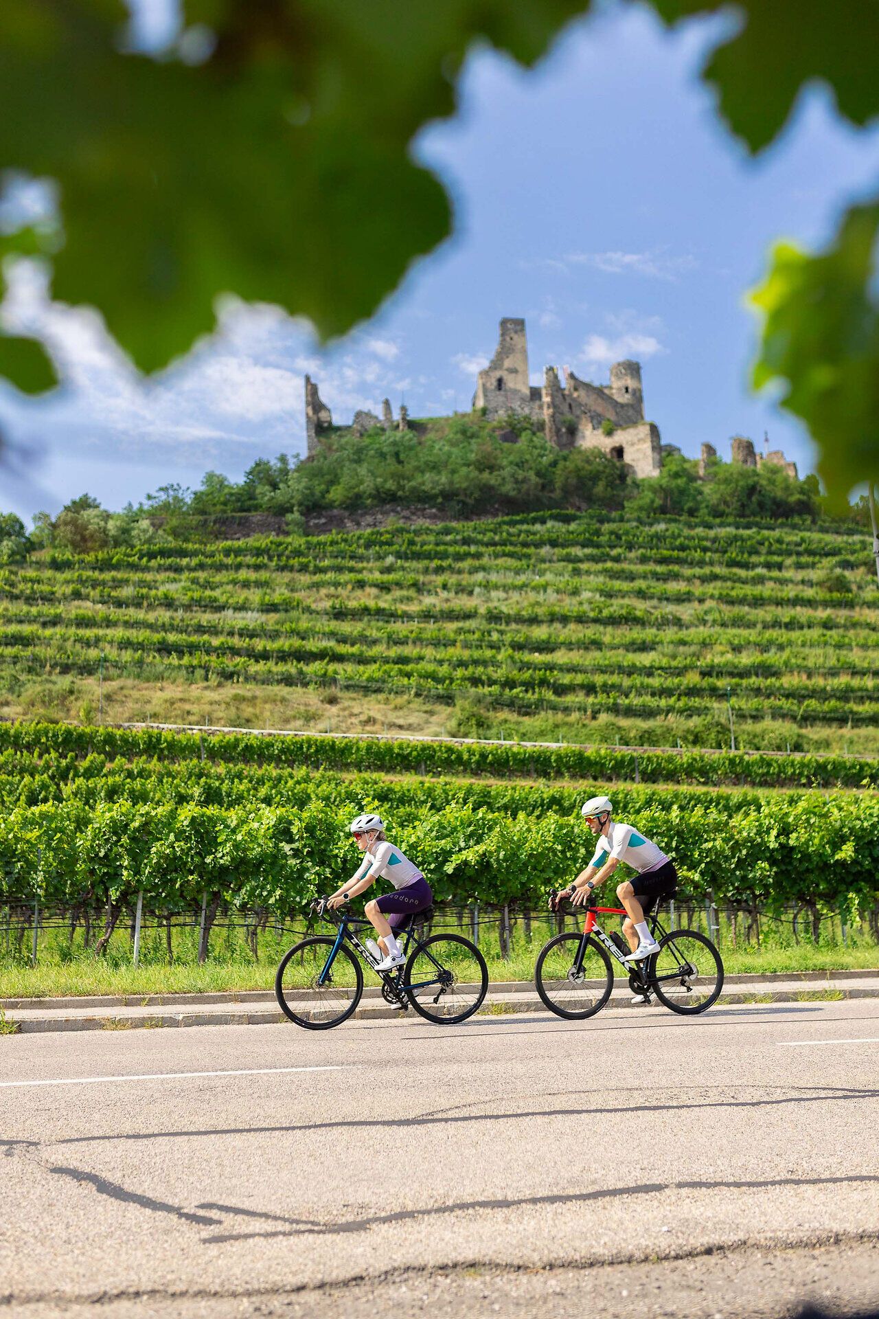 A couple ride their racing bikes on a road below the Senftenberg ruins.