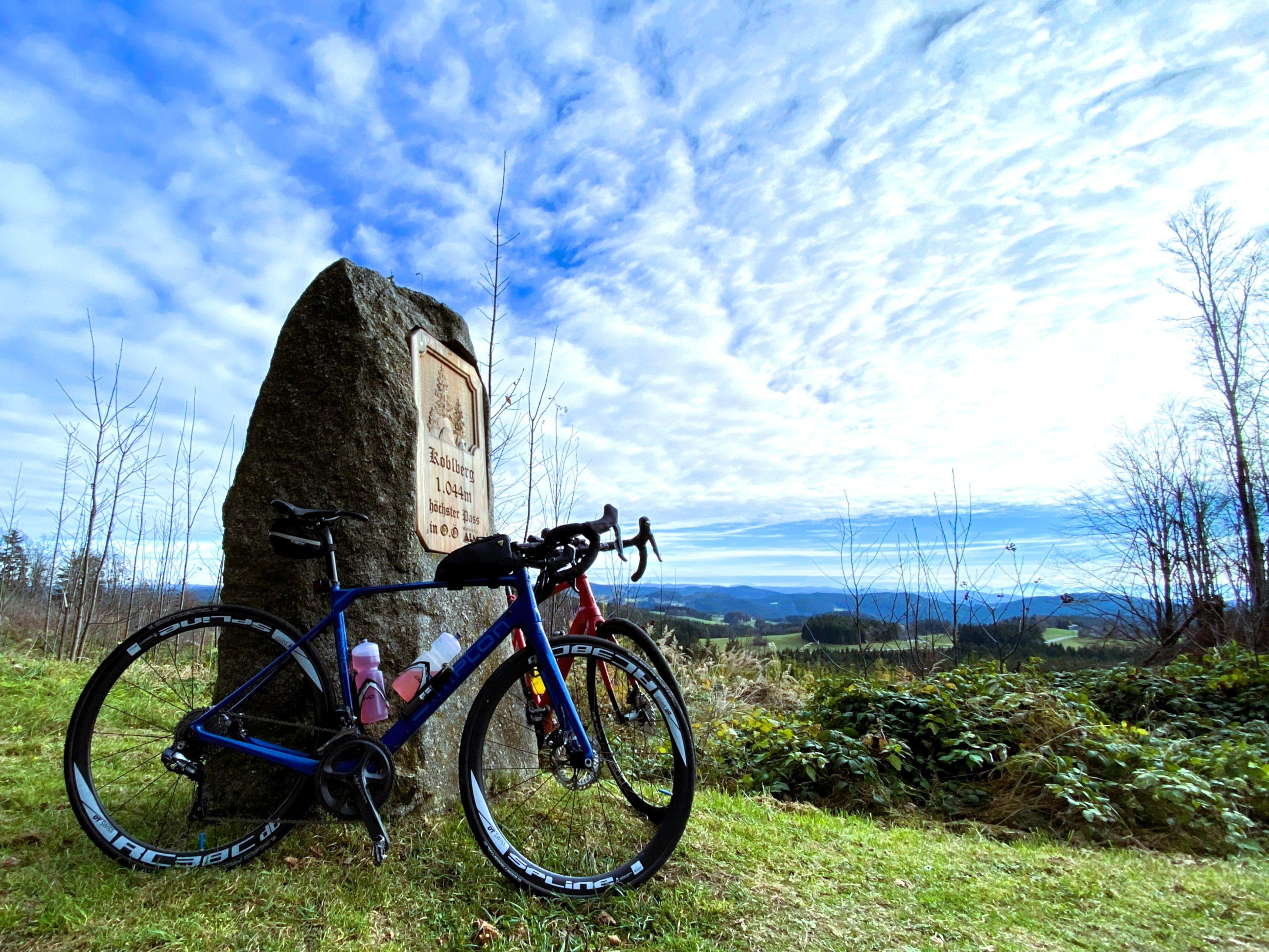 Two racing bikes leaning against a stone on a hill with a view over the landscape and mountains