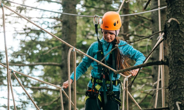 Child with helmet on rope bridge in climbing park.