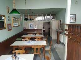 Interior view of a small, cozy restaurant with wooden furniture and green lamps.