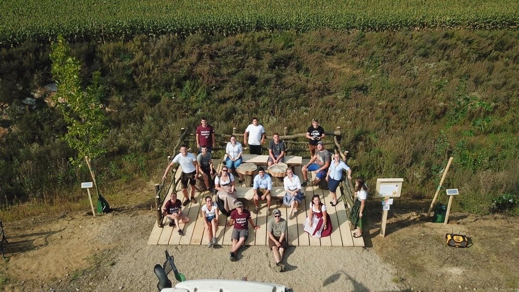Group of people on a wooden platform in a rural setting.
