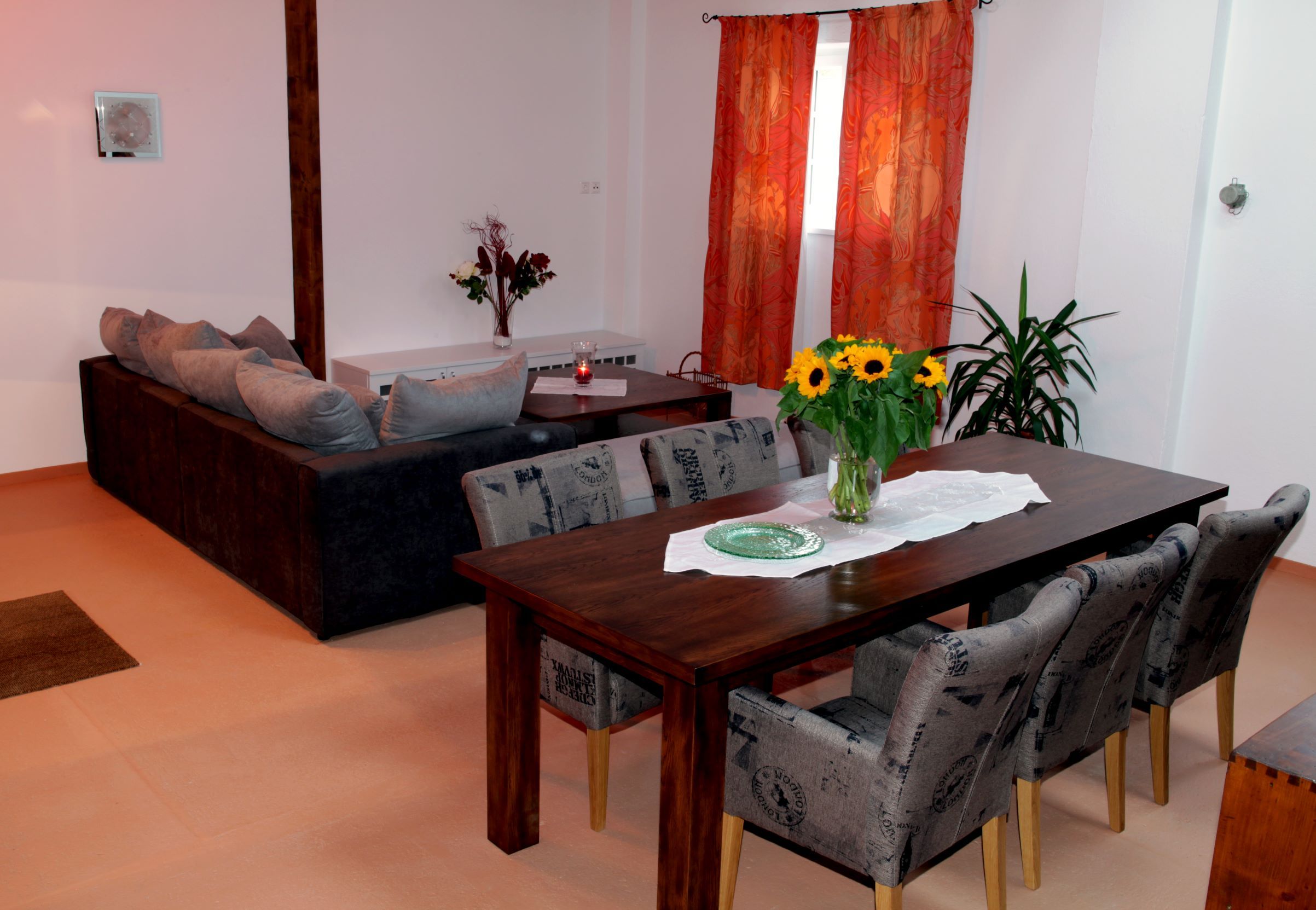 Living and dining area in a loft with wooden table, chairs, sofa and decorations.