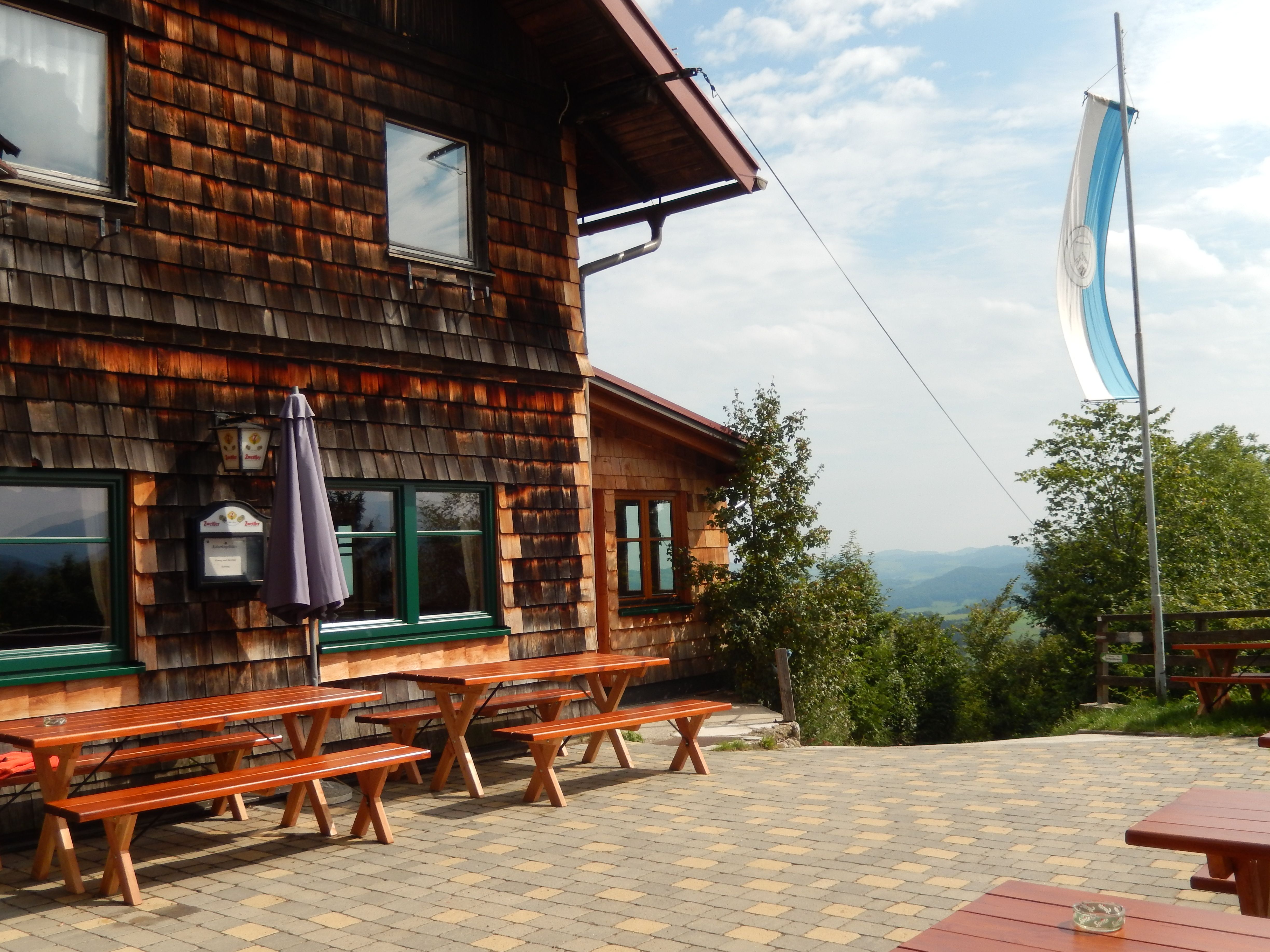 Wooden hut with terrace and benches, flag blowing in the wind.