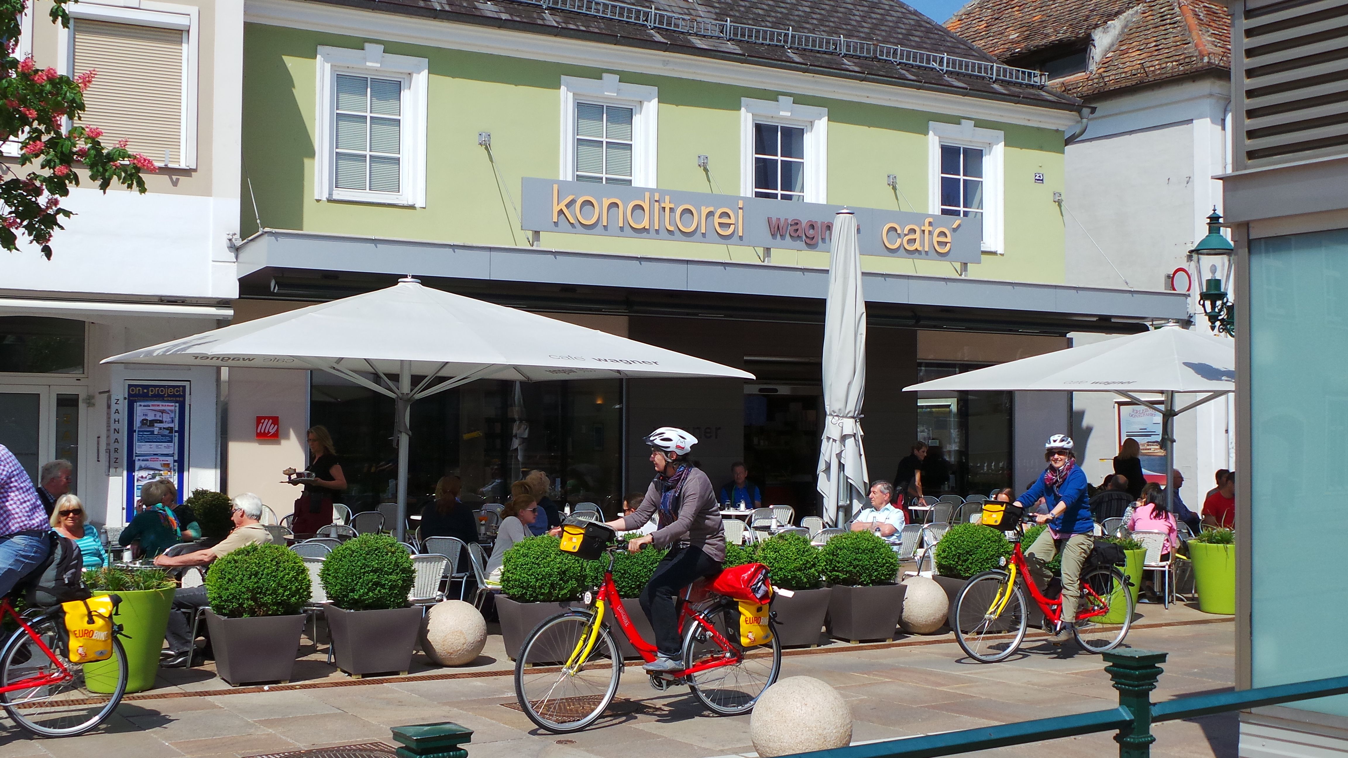 Exterior view of Konditorei Wagner with café and cyclists.