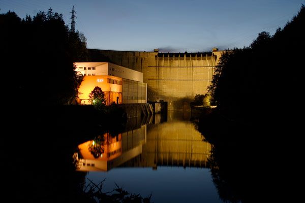 Night shot of the illuminated Ottenstein power station with reflection in the water.