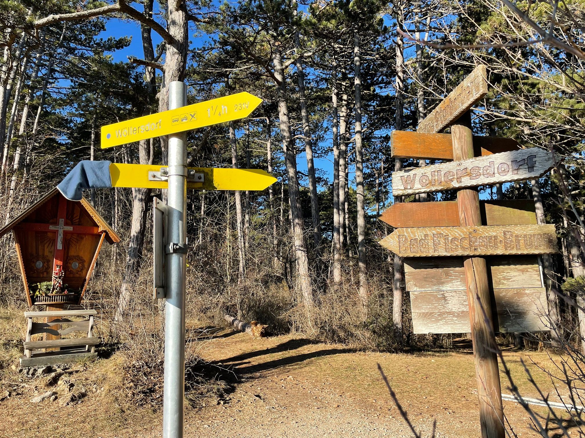 Signpost in the forest with a chapel in the background.