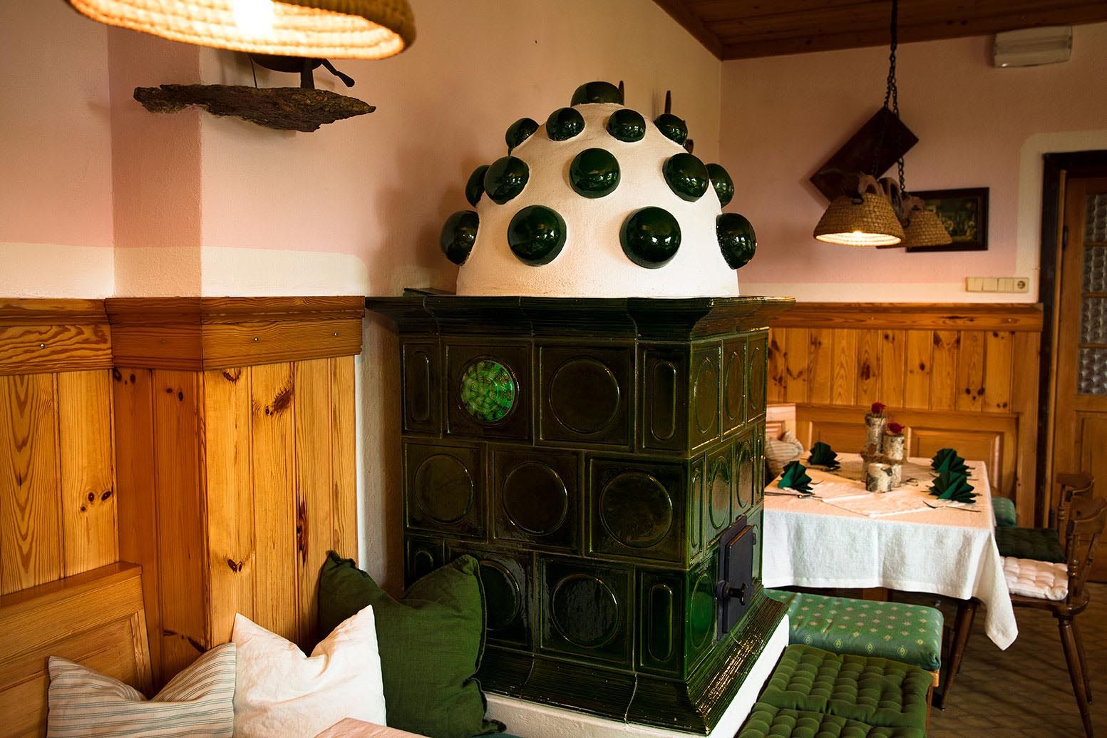 Cozy, traditional parlor with green tiled stove and wooden furniture.