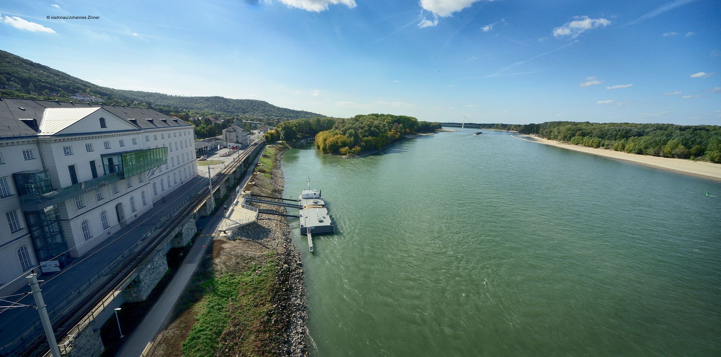 View of the Danube at Hainburg with landing stage and buildings on the bank.