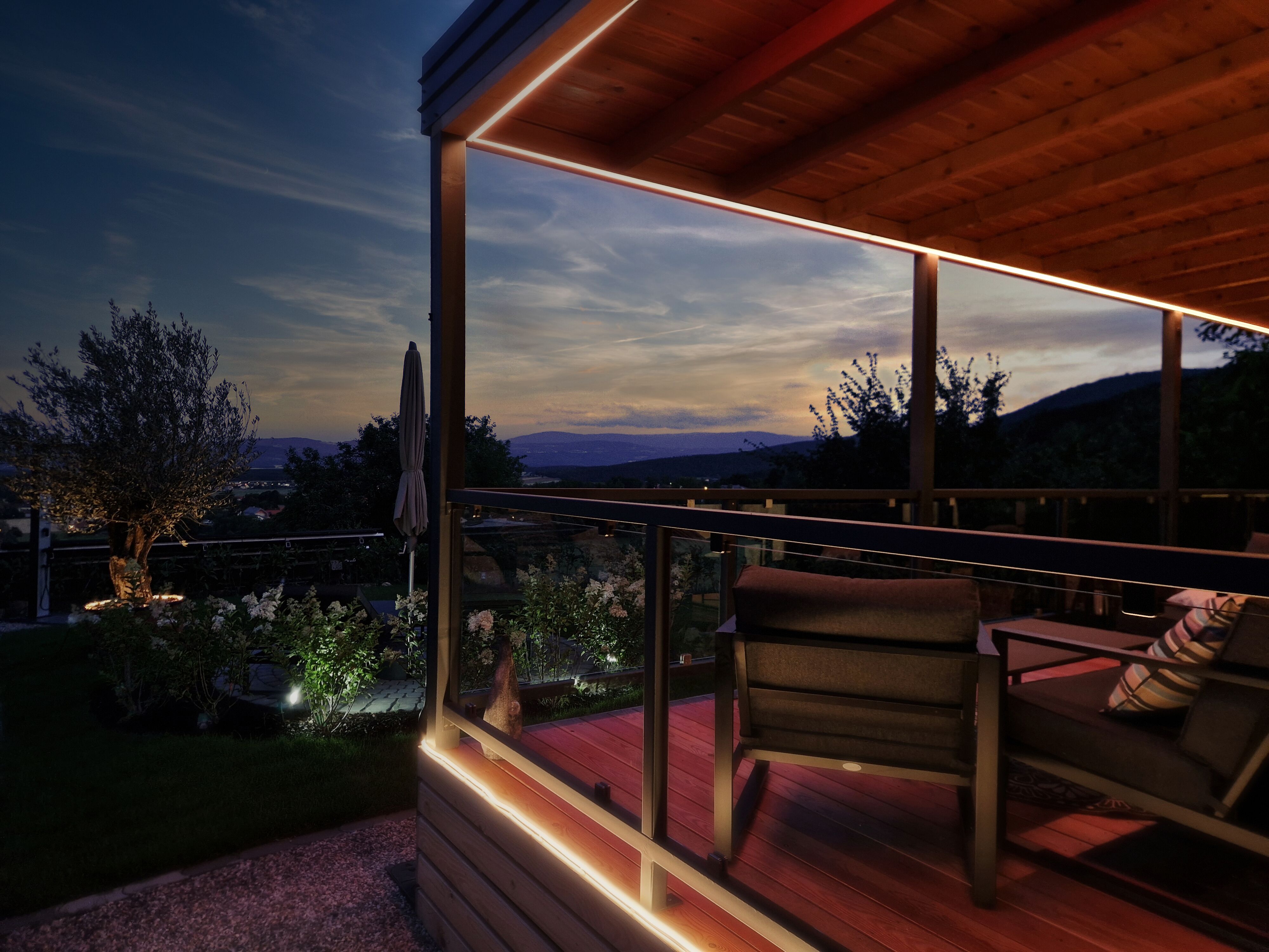 Evening atmosphere on a terrace with a view of the mountains and a garden.