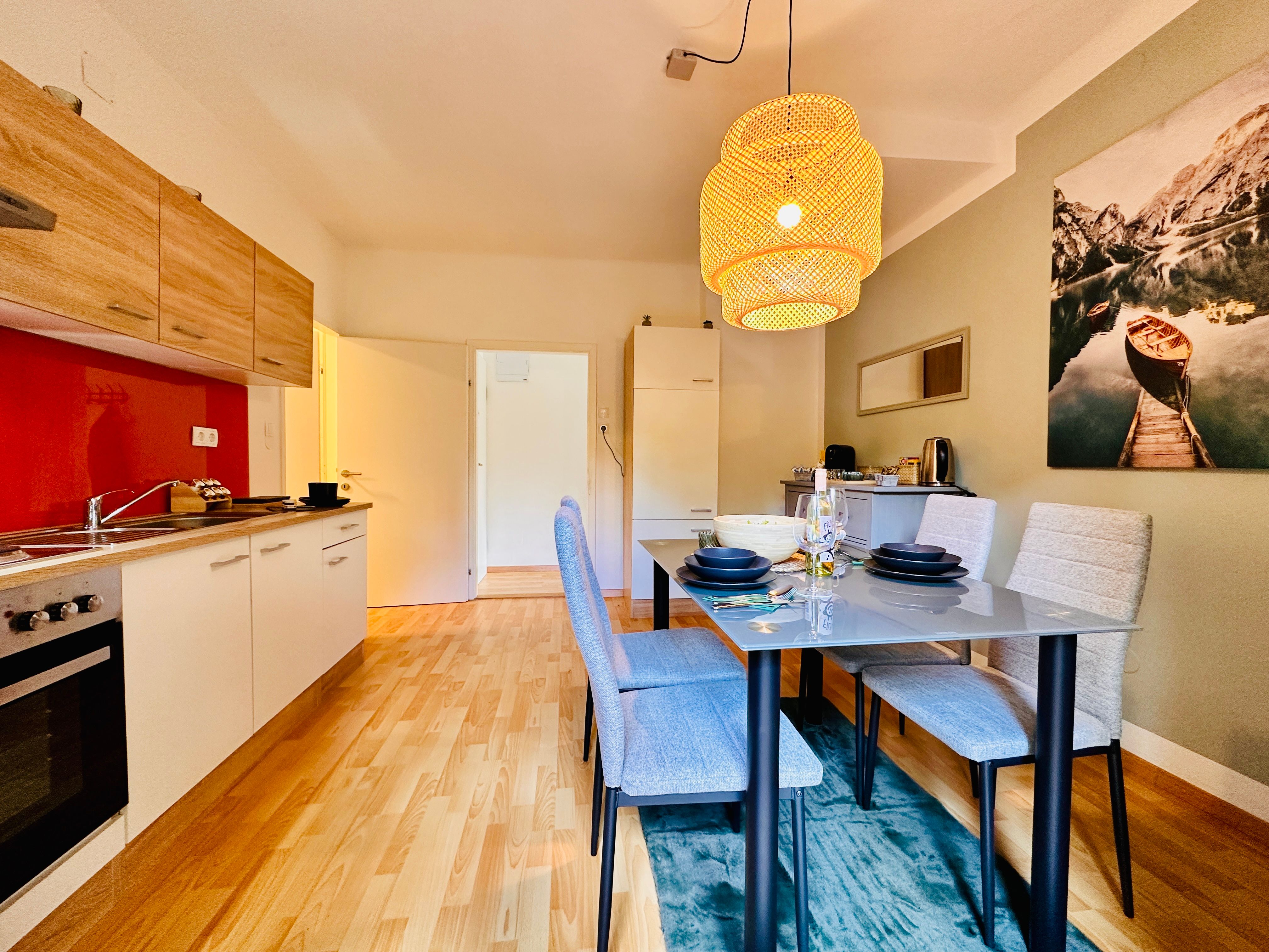 Modern kitchen with dining table and hanging lamp.