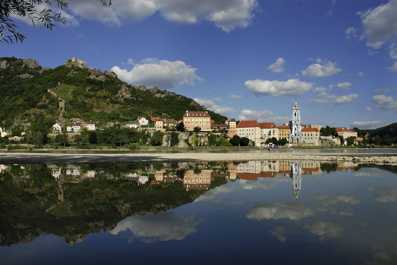 Panorama of Dürnstein with the Danube in the foreground and the castle ruins on a hill in the background.