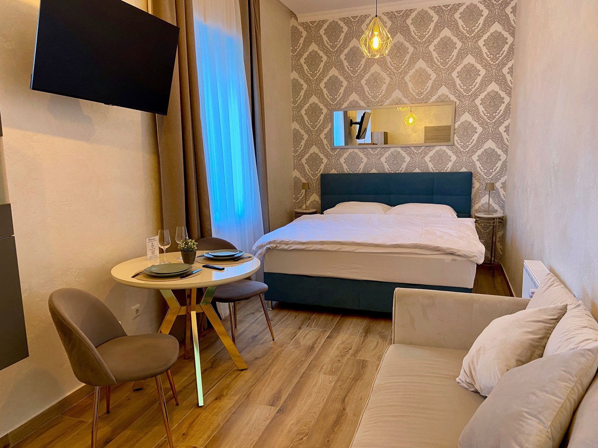 A cozy hotel room with double bed, small dining table and sofa.