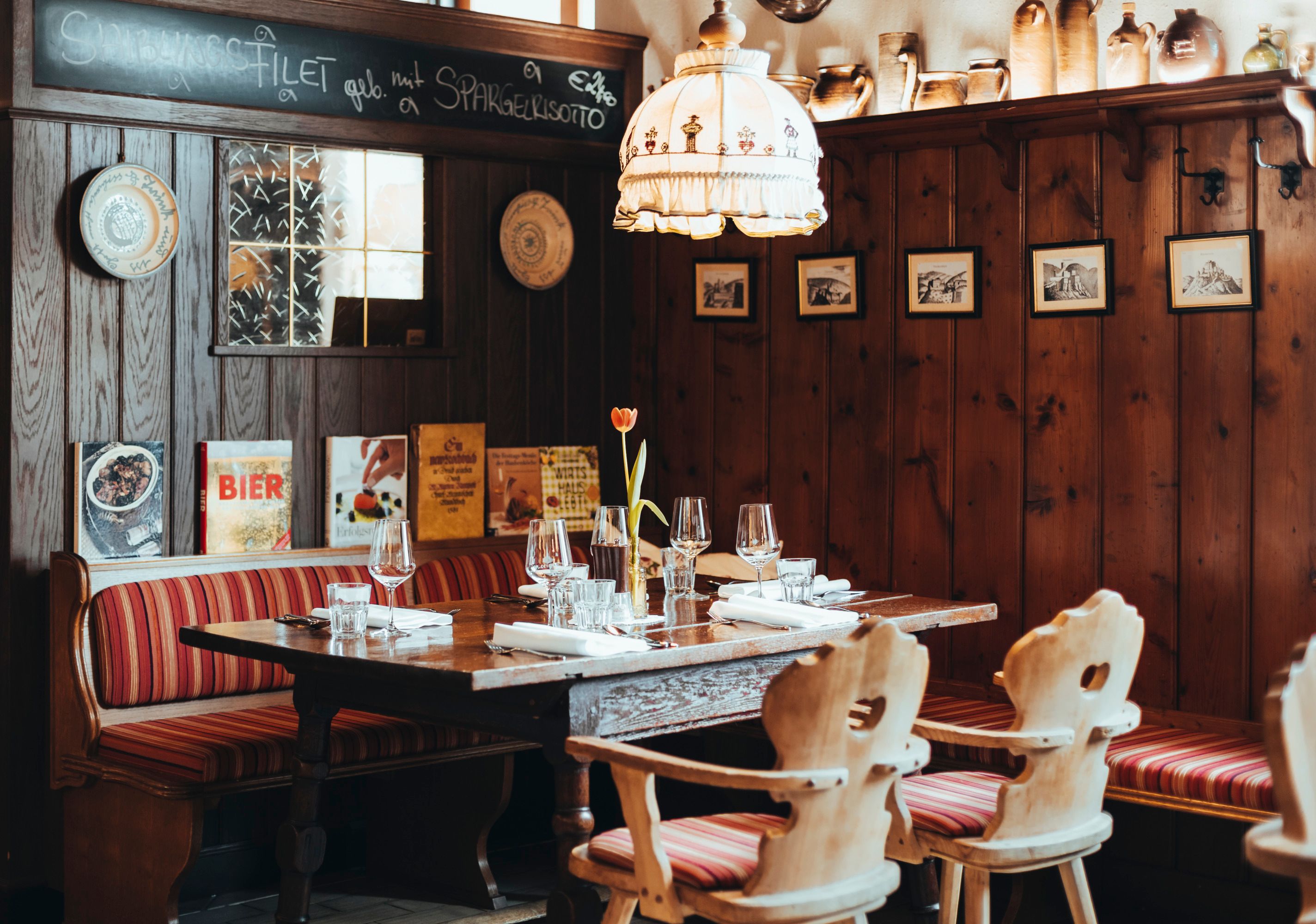 Cozy restaurant with wooden walls, red striped benches and a table setting.