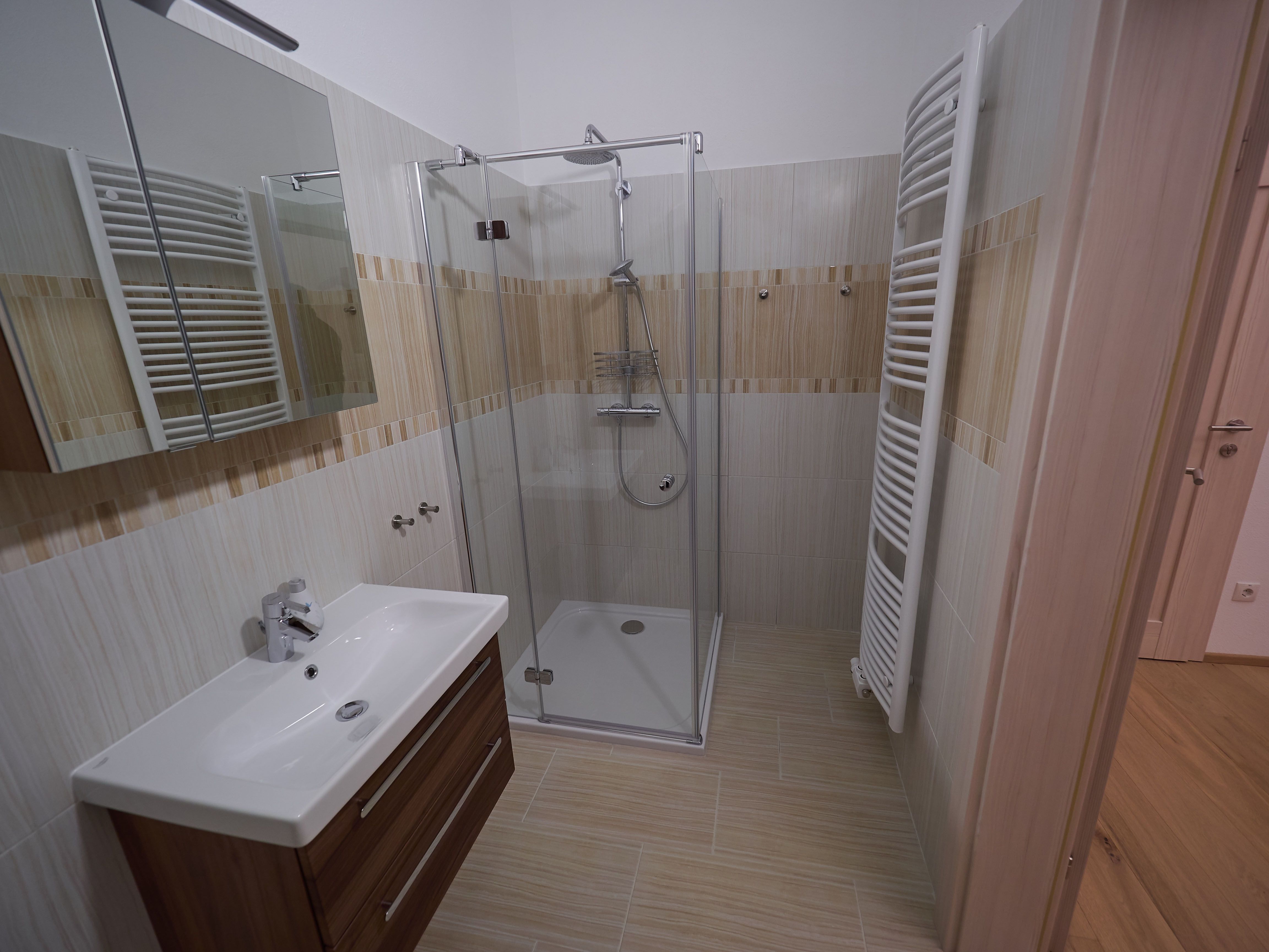 Modern bathroom with shower, washbasin and towel radiator.