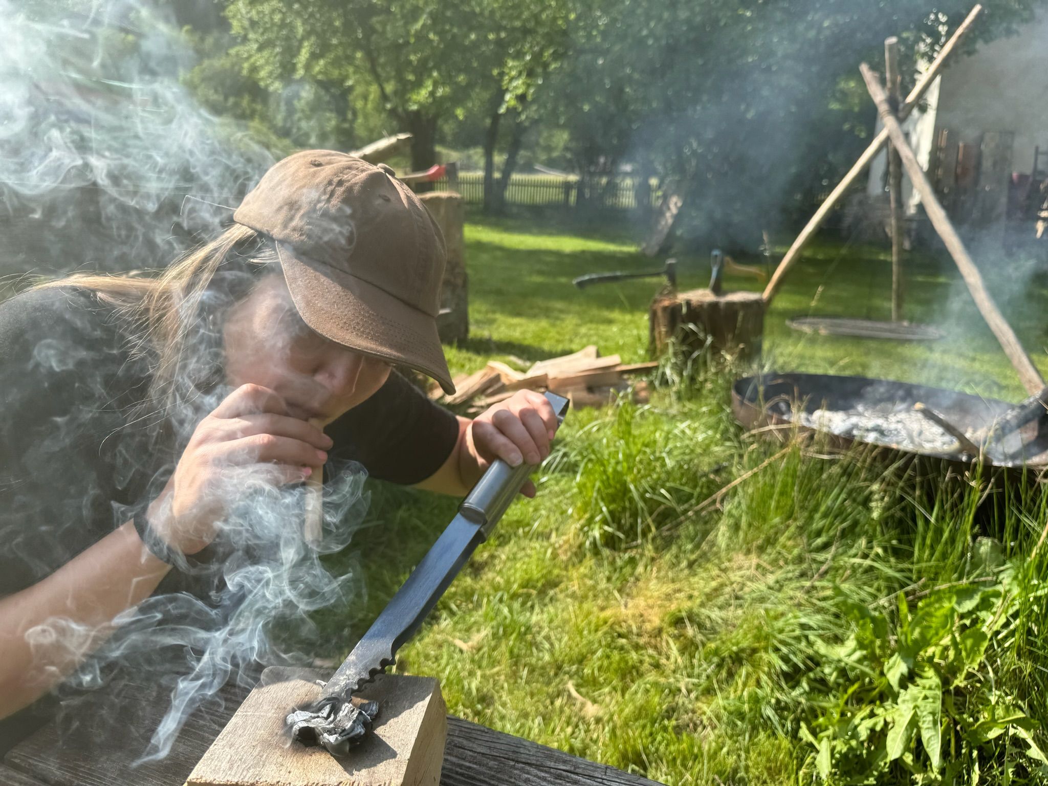Person lights fire with knife and wood outdoors.