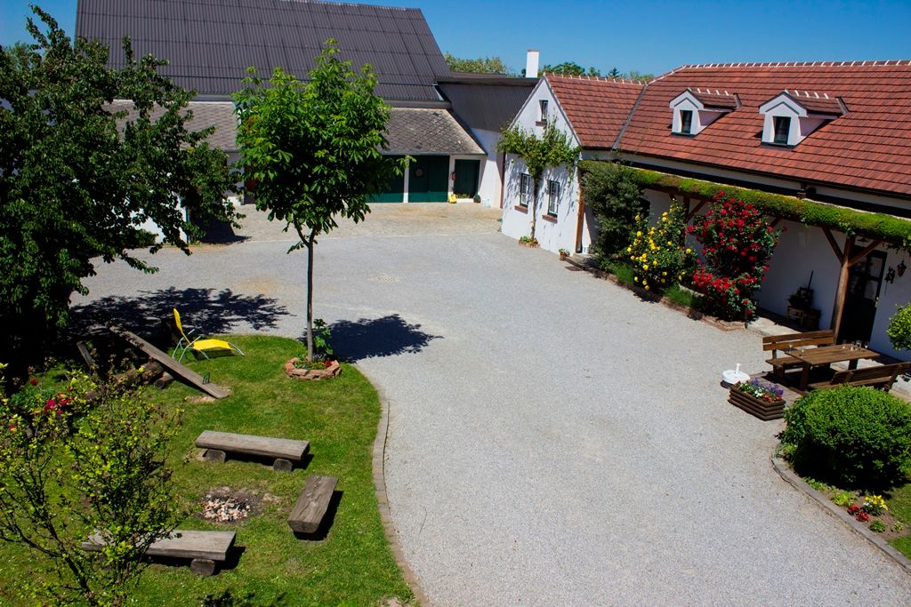 A well-kept courtyard with trees, flowers and seating, surrounded by buildings with red roofs.