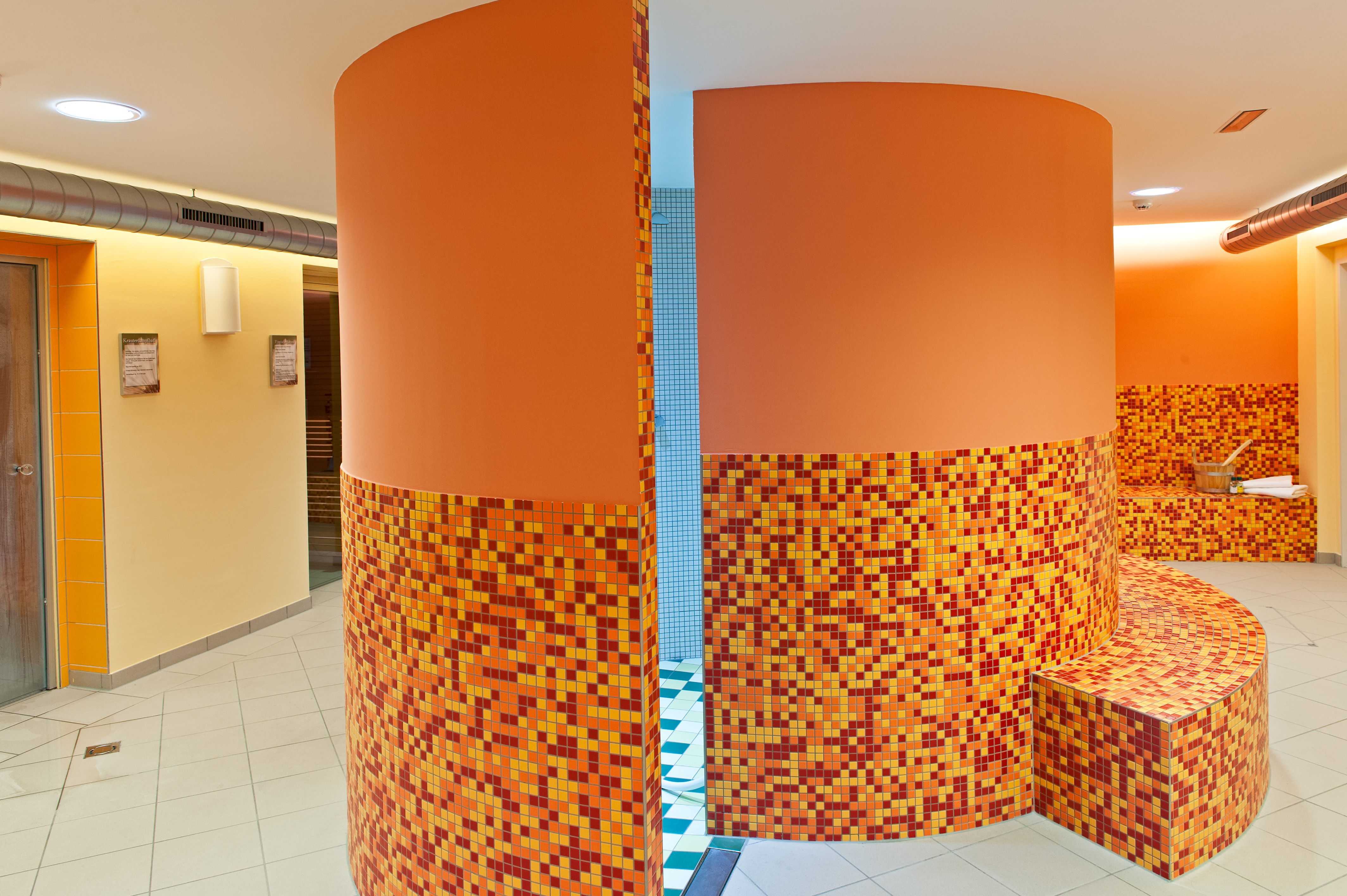 Interior view of a wellness area with orange mosaic tiles and round walls.