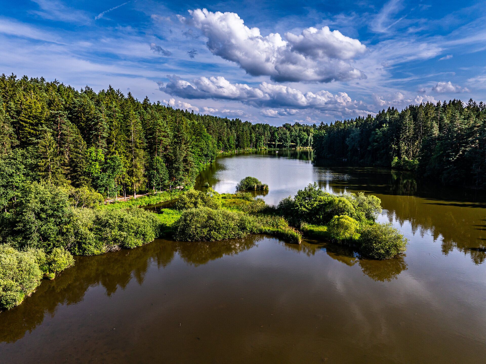 Umgeben von üppigem Grün und dem sanften Plätschern des Wassers, lädt die malerische Landschaft zu einem entspannten Aufenthalt ein. Die Wolken spiegeln sich im ruhigen Wasser und schaffen eine harmonische Atmosphäre, die zum Verweilen einlädt. Hier, wo Natur und Kultur aufeinandertreffen, wird jeder Moment zum unvergesslichen Erlebnis.
