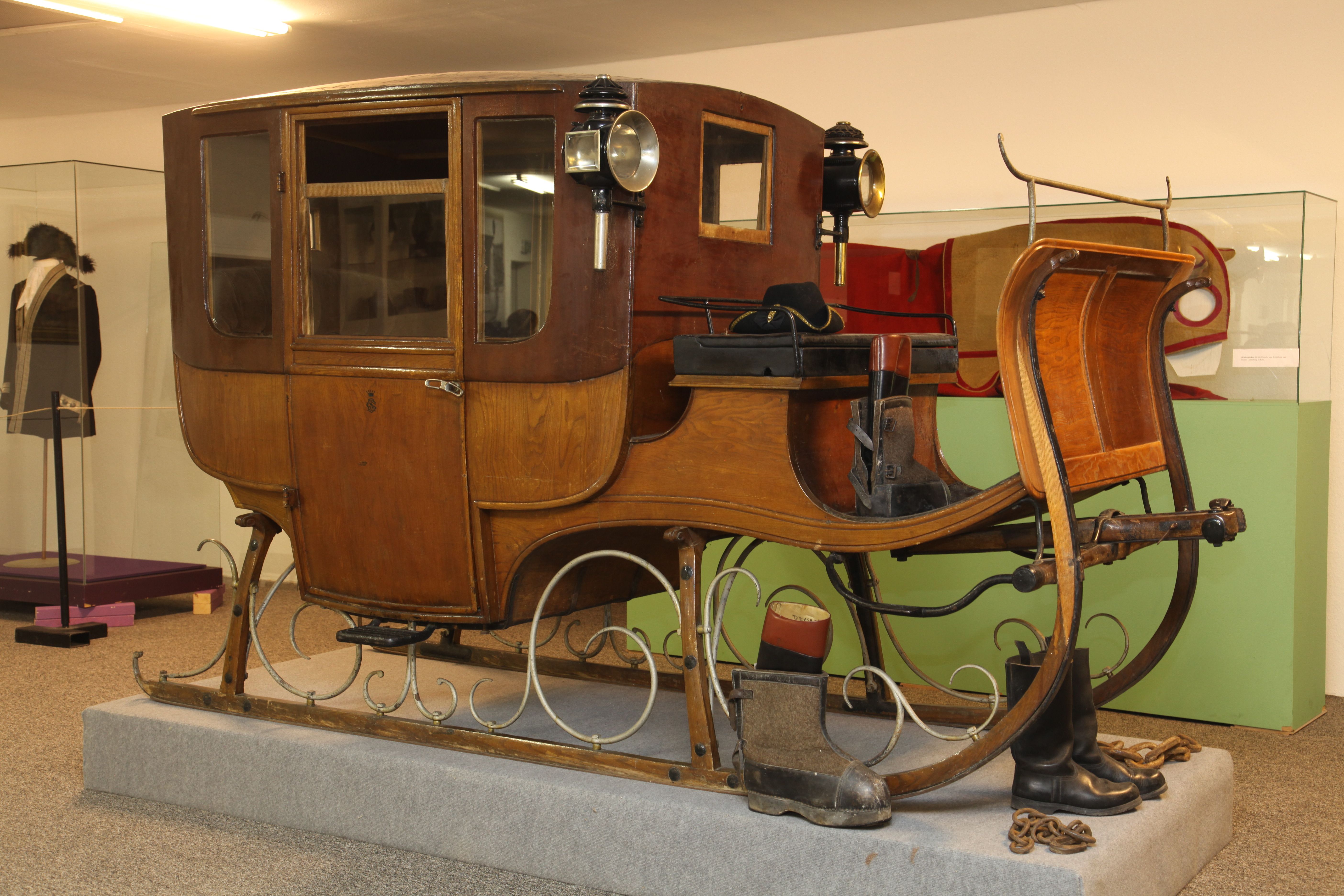 An antique wooden traveling sledge with lanterns, exhibited in a museum.