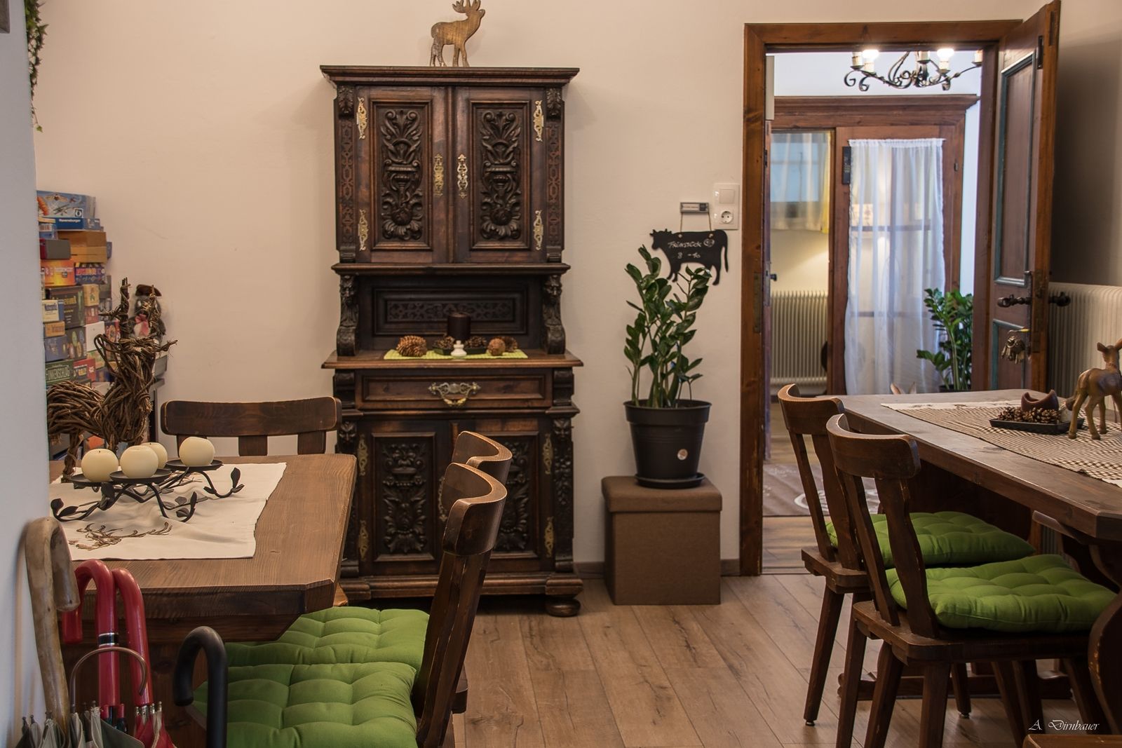 Cozy lounge with wooden furniture, green seat cushions and decorative cupboard.