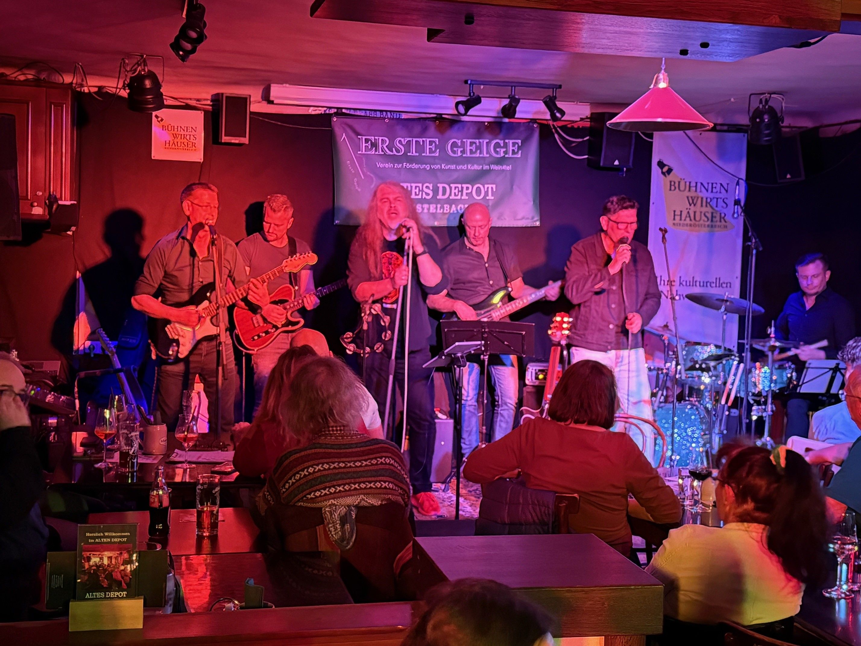 Band plays on a stage in a small venue with an audience.