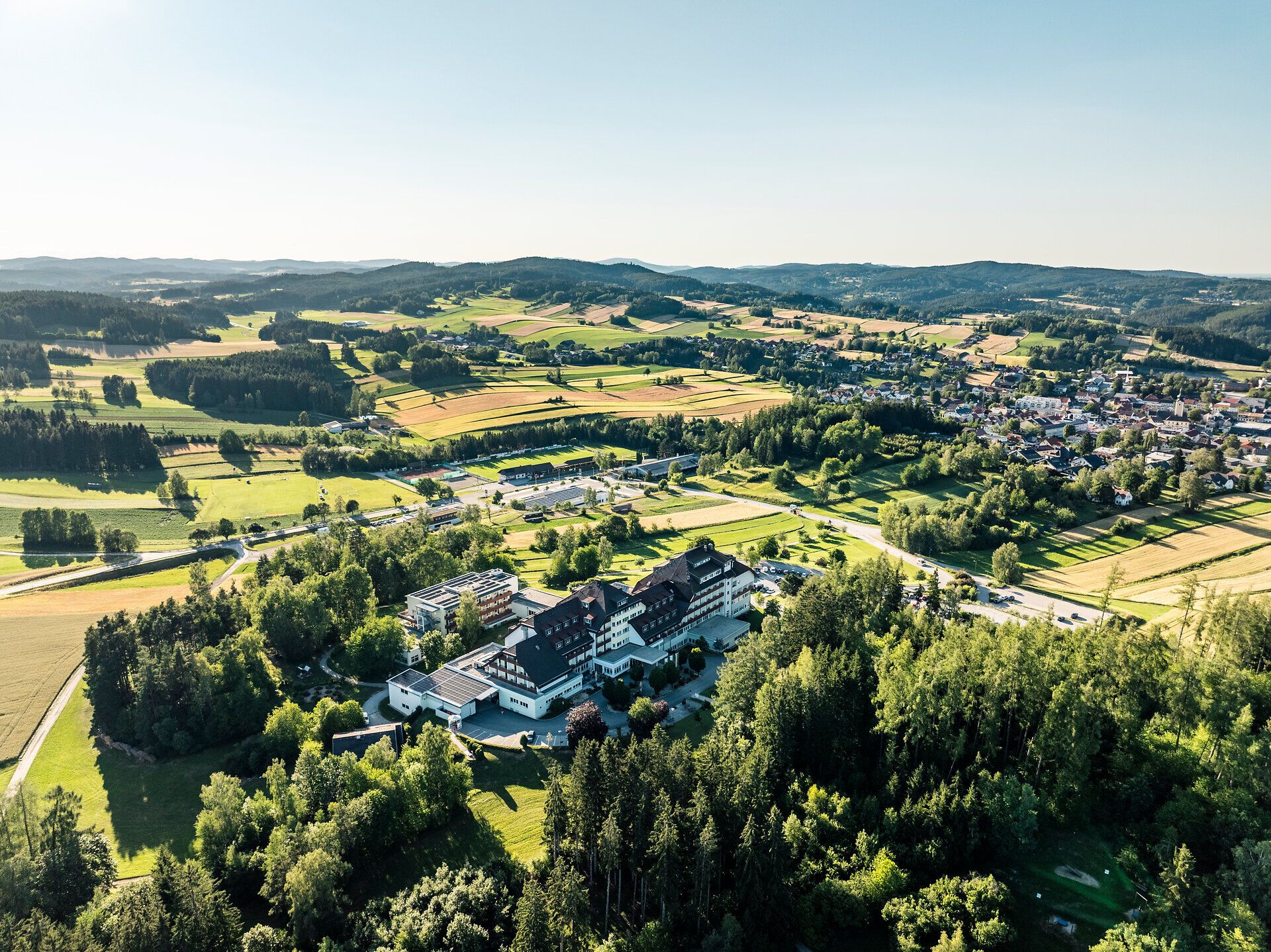 Aerial view of the Groß Gerungs Cardiovascular Center in the Waldviertel region, surrounded by meadows, fields, forests, and the town of Groß Gerungs.